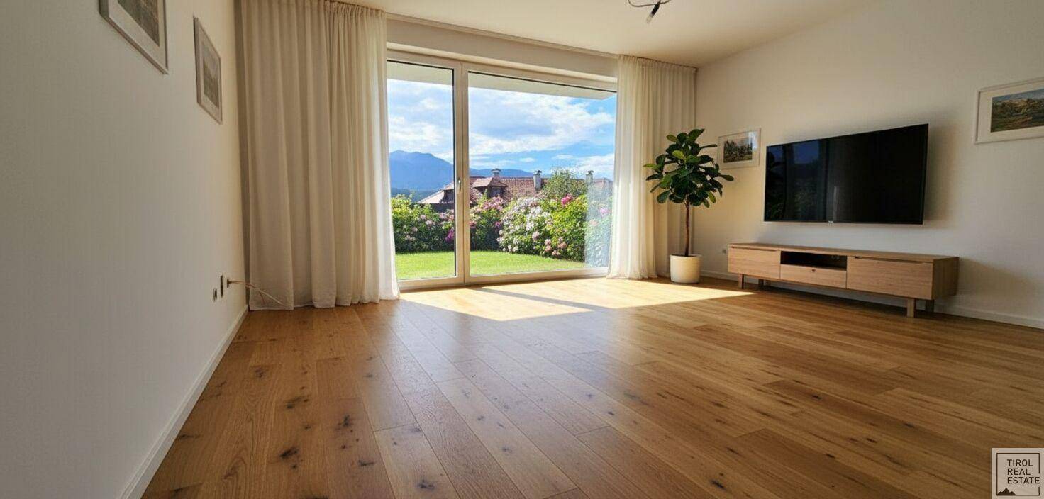 Geräumiges Wohnzimmer mit Holzboden und direktem Zugang zum grünen Garten.