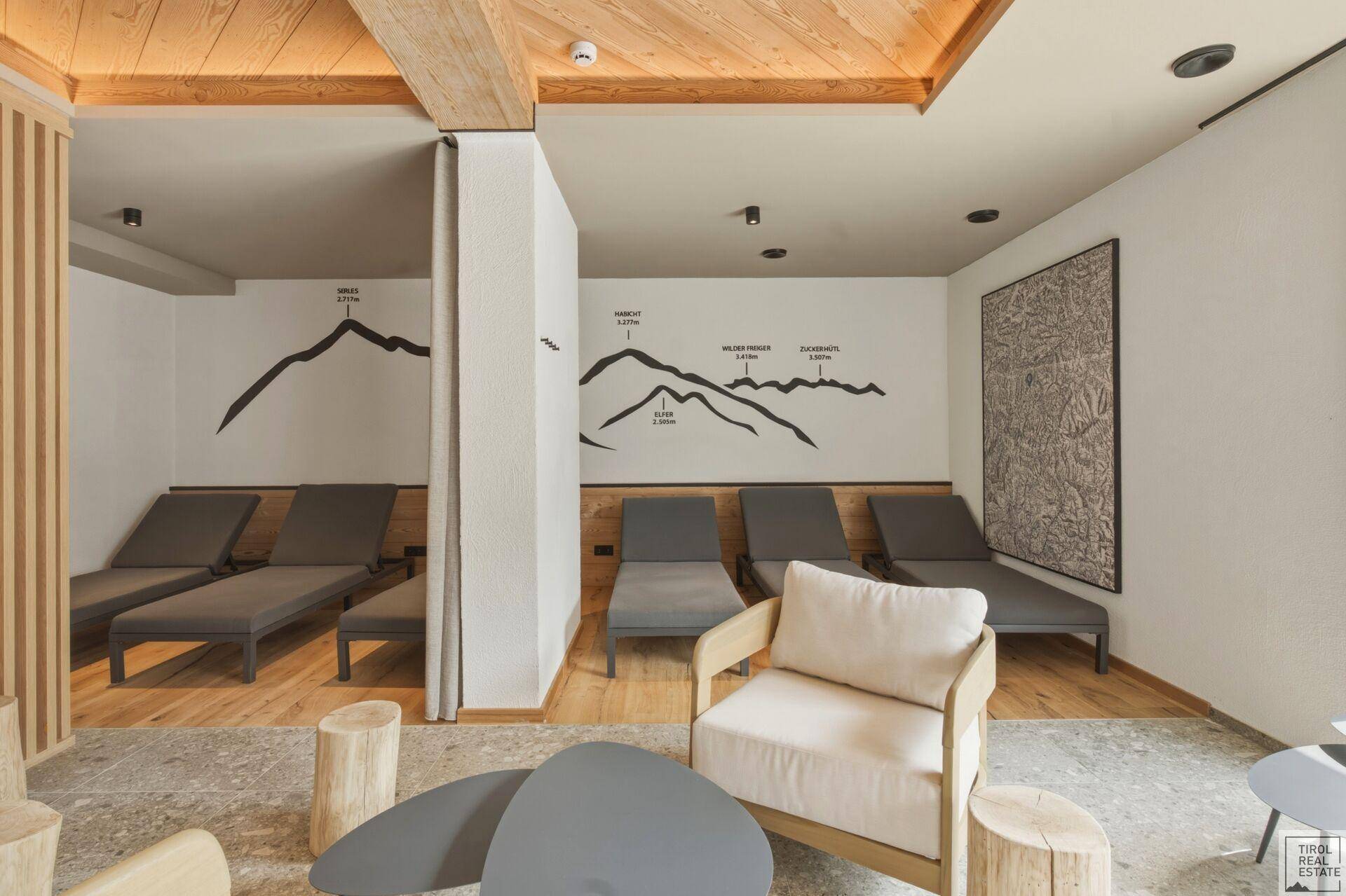 Gemütlicher Ruheraum mit bequemen Liegen, Holzelementen und Bergmotiven an der Wand.