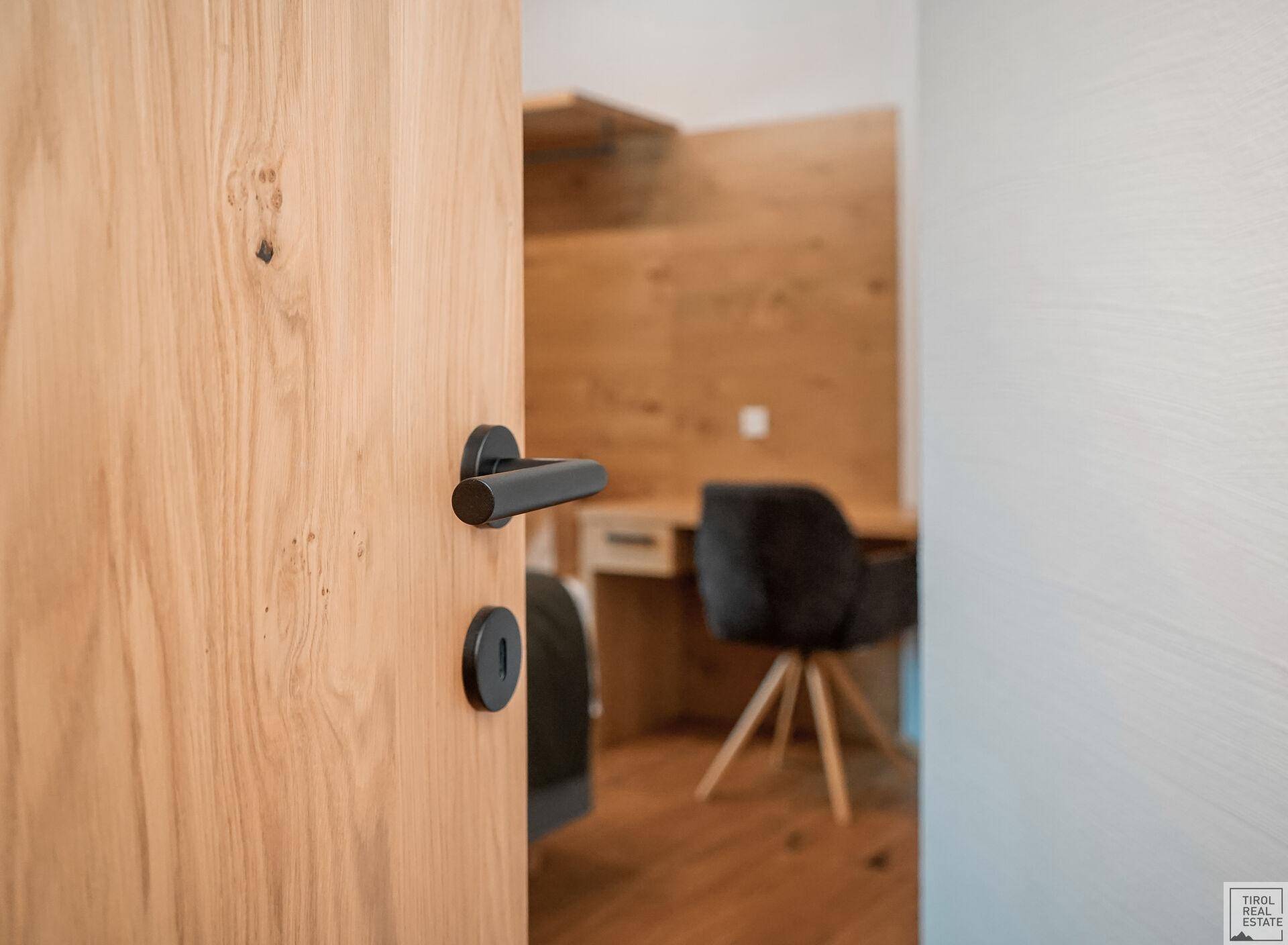 Holztür öffnet sich zu einem Raum mit Schreibtisch und Holzboden.