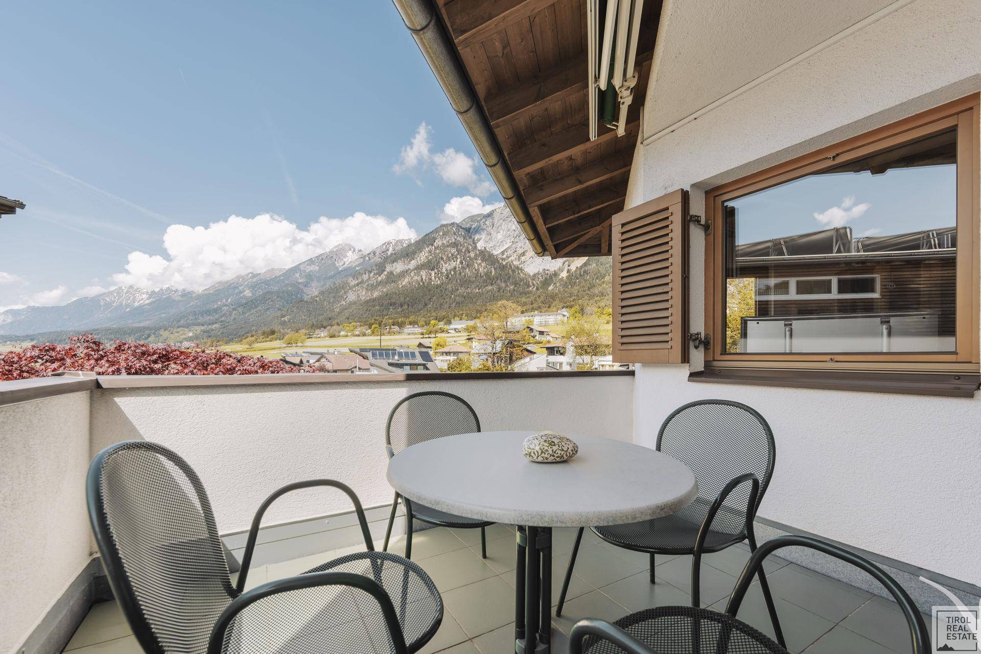 Sonniger Balkon mit Sitzgelegenheiten und atemberaubendem Panoramablick auf die Berge.