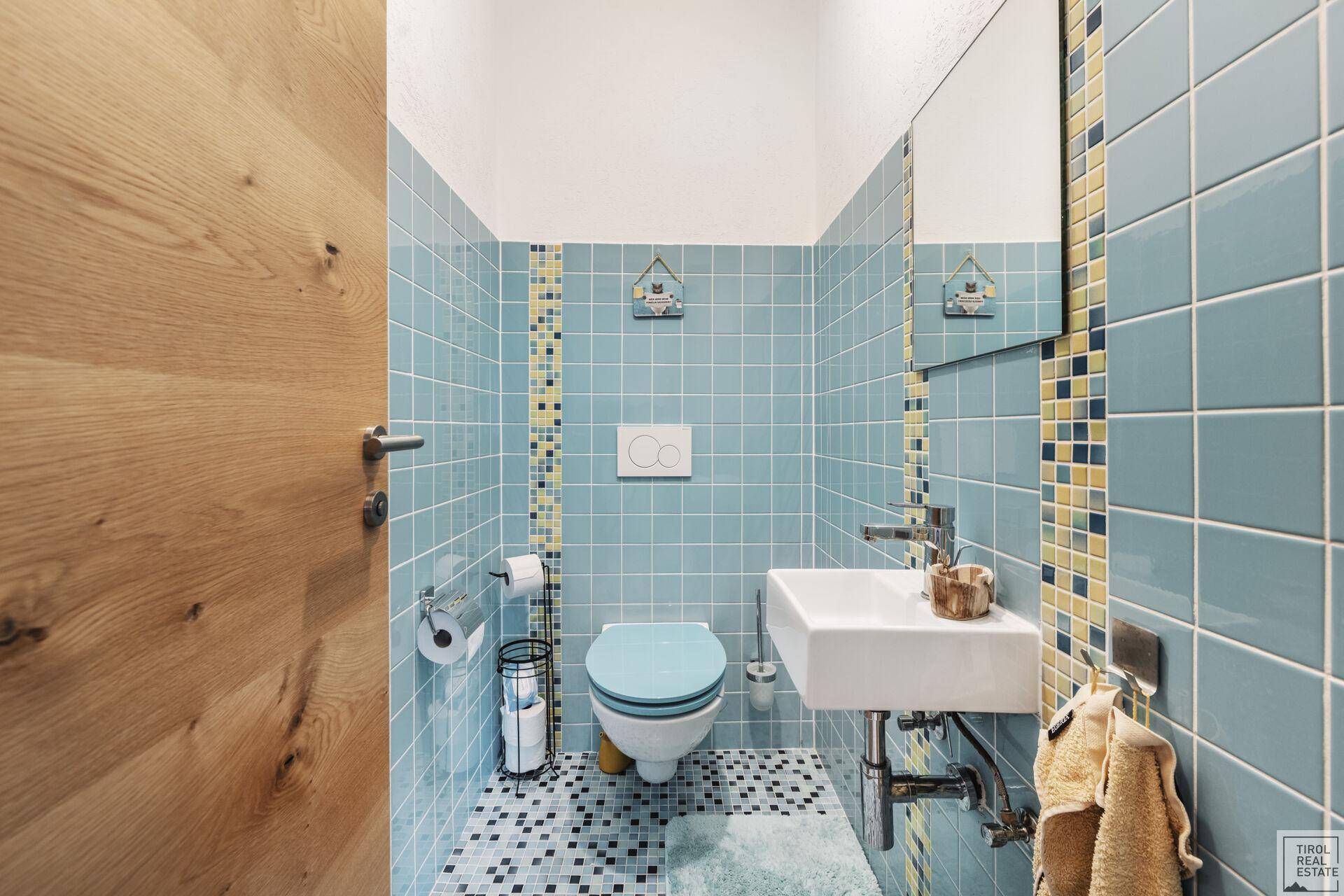 Kleines Gäste-WC mit blauen Fliesen und modernem Waschbecken.