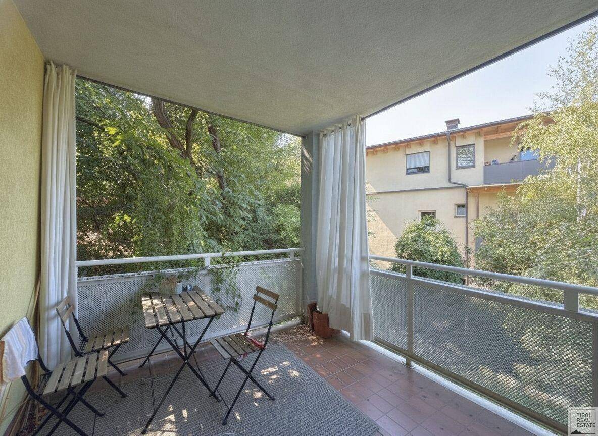 Möblierter Balkon mit Blick ins Grüne und auf umliegende Gebäude, ideal für entspannte Stunden im Freien.