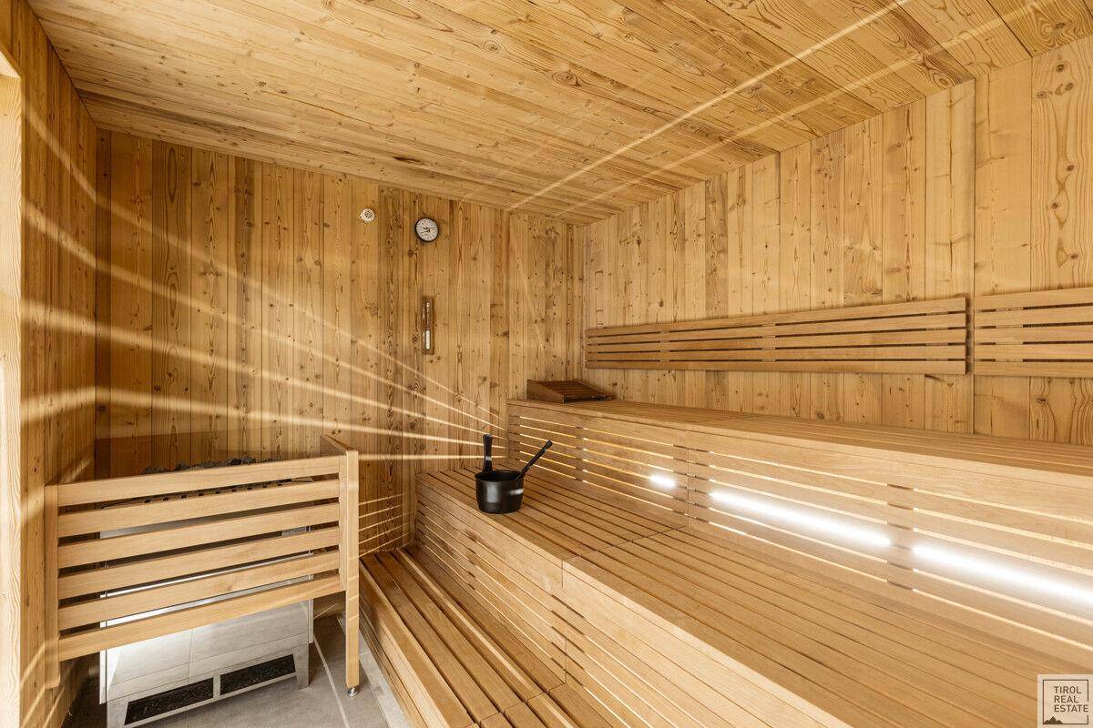 Geräumige Holzsauna mit mehreren Bänken und traditionellem Saunaofen.