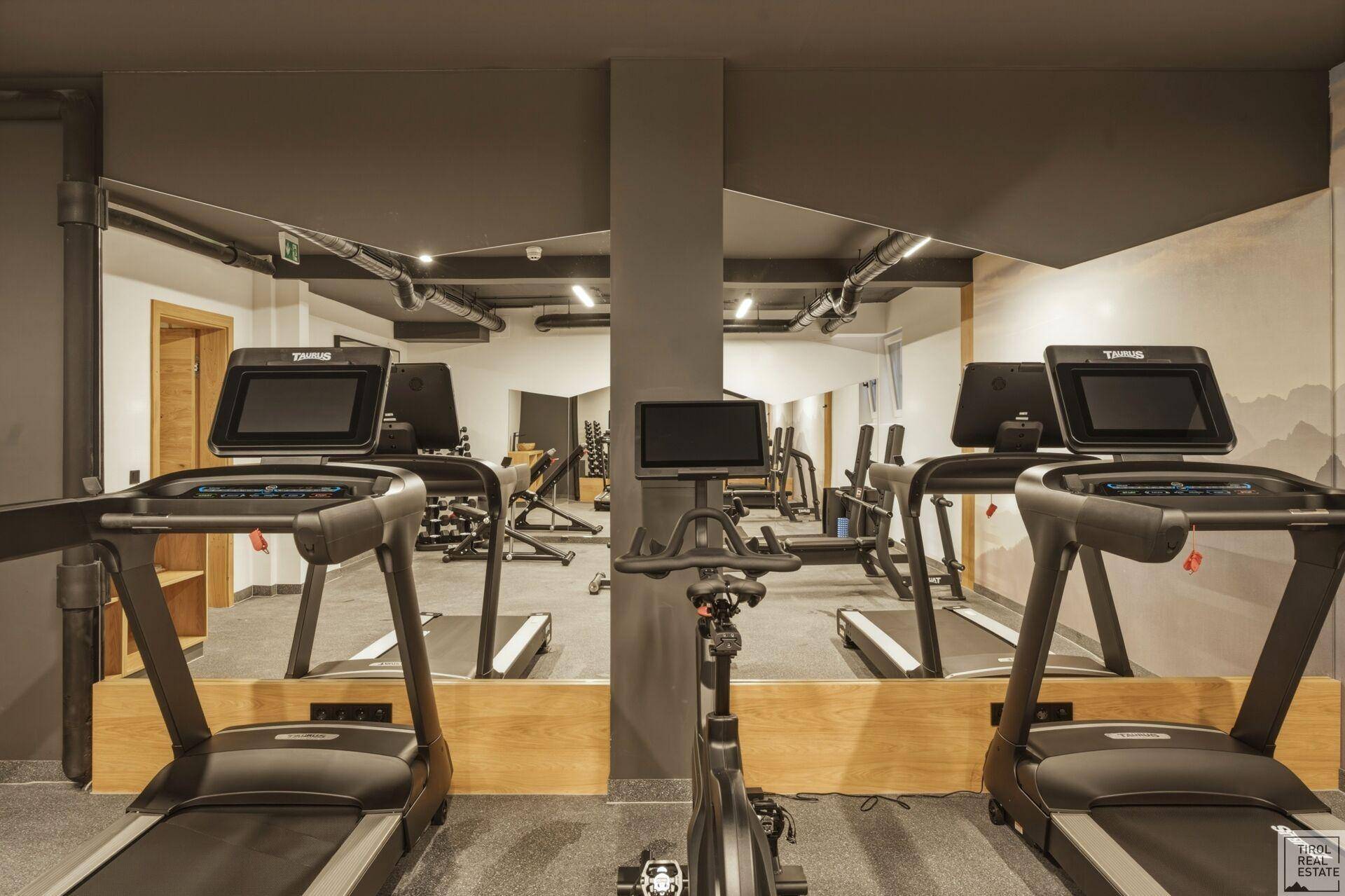 Moderner Fitnessraum mit Laufbändern, Fahrrädern und Spiegelwänden für ein umfassendes Training.