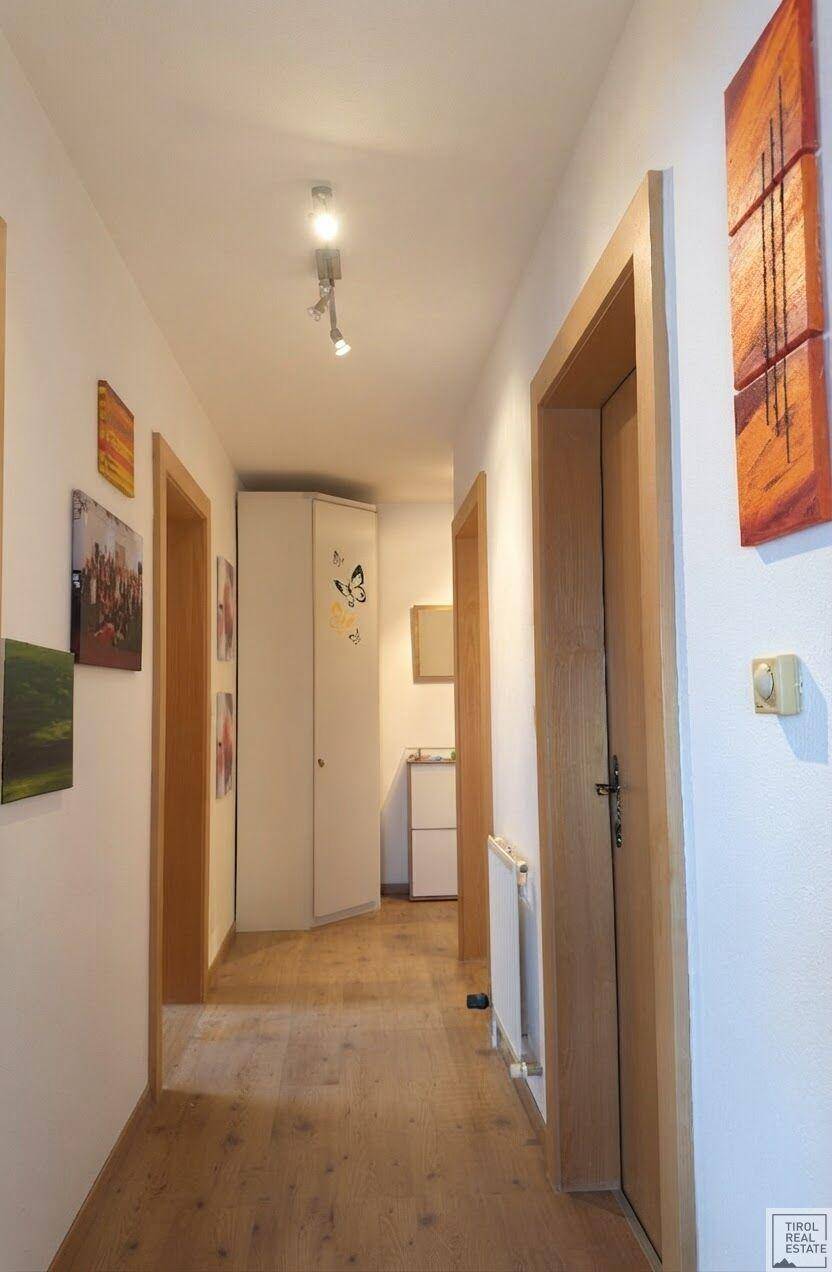 Heller Flur mit Holzboden, Holztüren und dekorativen Bildern an den Wänden.