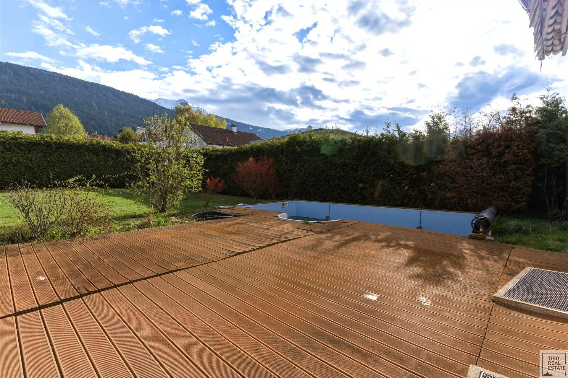 Weitläufige Holzterrasse am Pool, bereit für entspannte Stunden im Freien mit Bergblick.