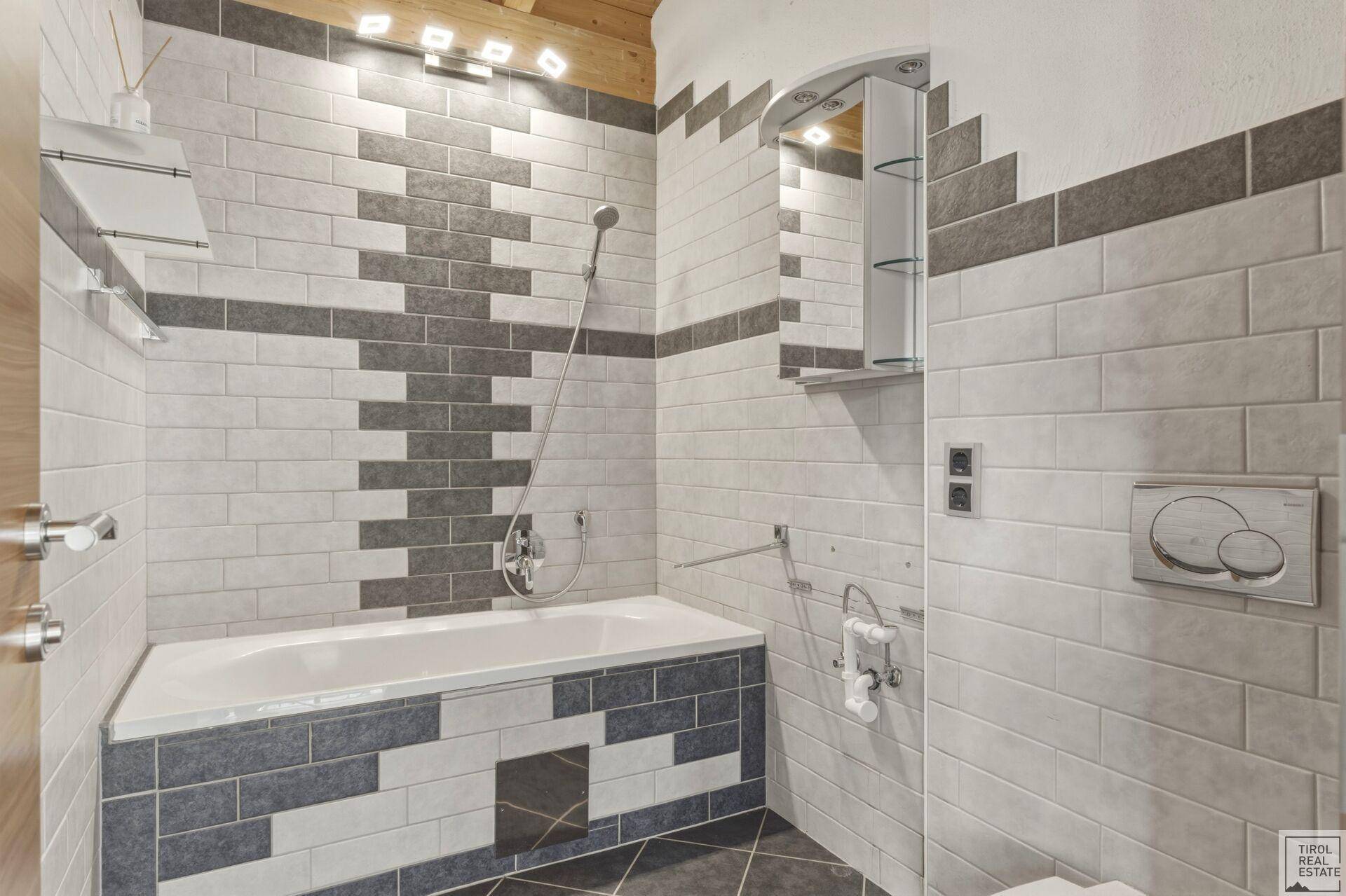 Funktionales Badezimmer mit Badewanne und Duschfunktion, ausgestattet mit modernen Fliesen.