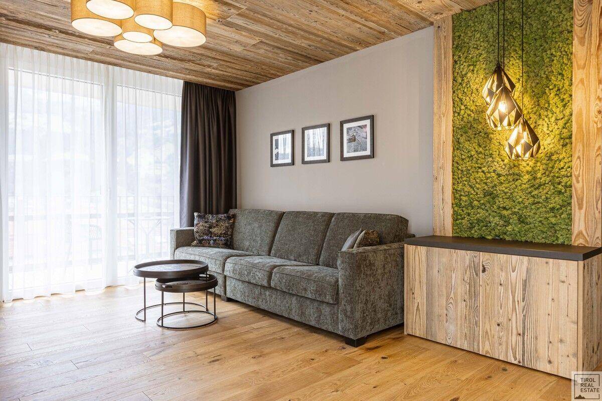 Helles Wohnzimmer mit Holzbalkendecke, gemütlichem Sofa und dekorativer Mooswand.