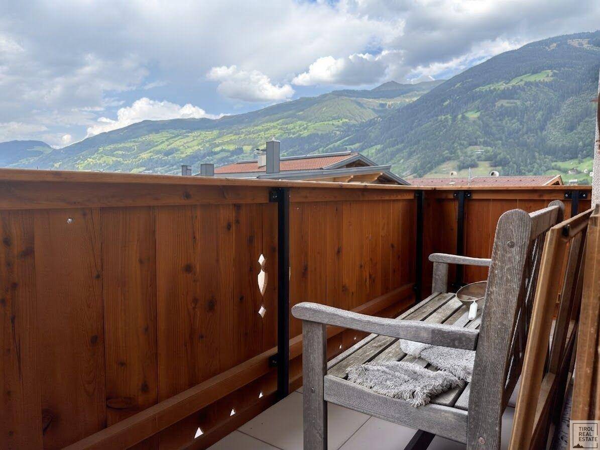 Balkon mit rustikaler Holzbank und schöner Aussicht auf die umliegenden Berge.