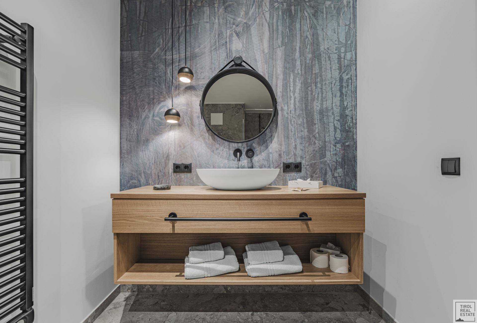 Detailansicht des modernen Badezimmerwaschtischs mit runden Spiegeln und stilvollen Pendelleuchten.