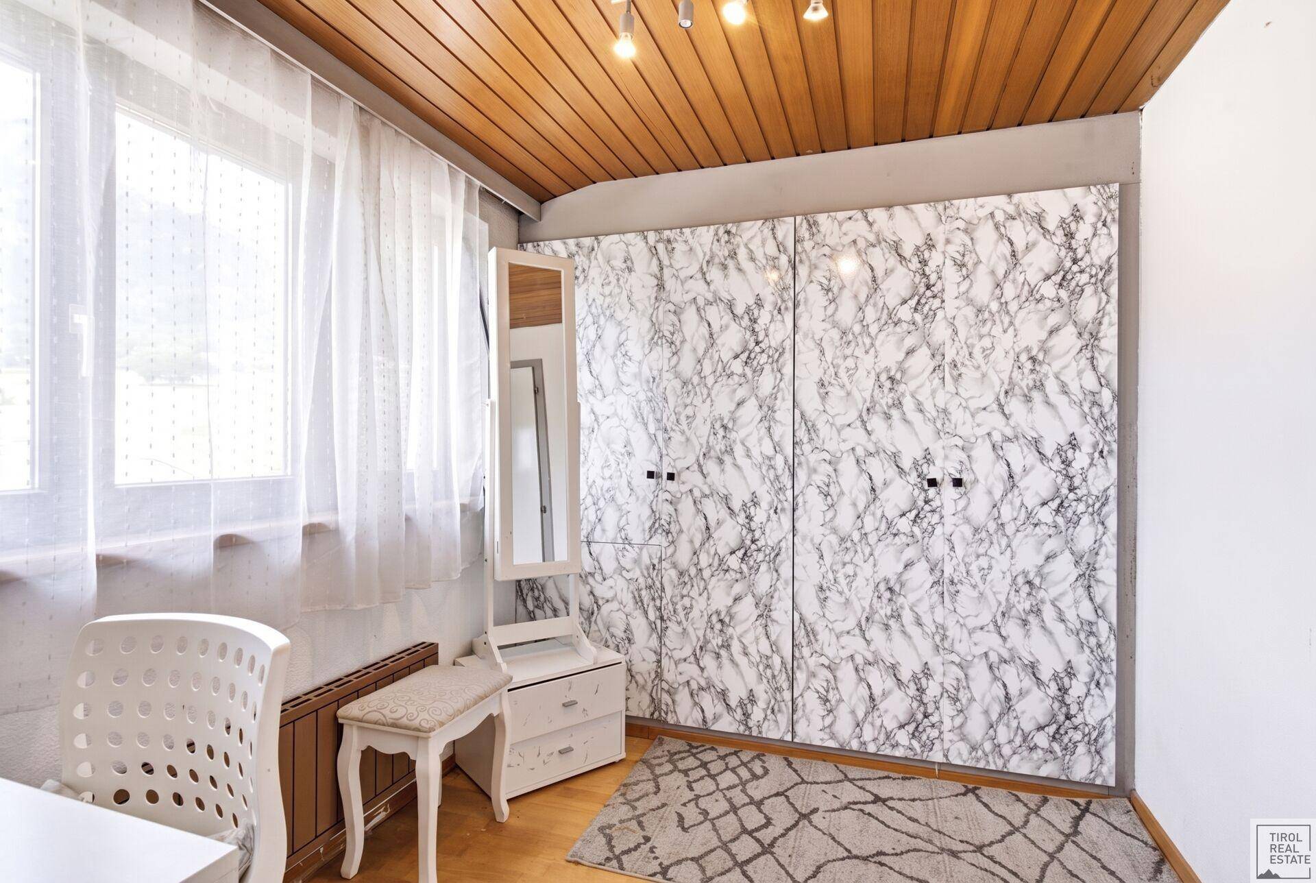 Schlafzimmer mit Holzdachschräge, Einbauschränken und Fenster.