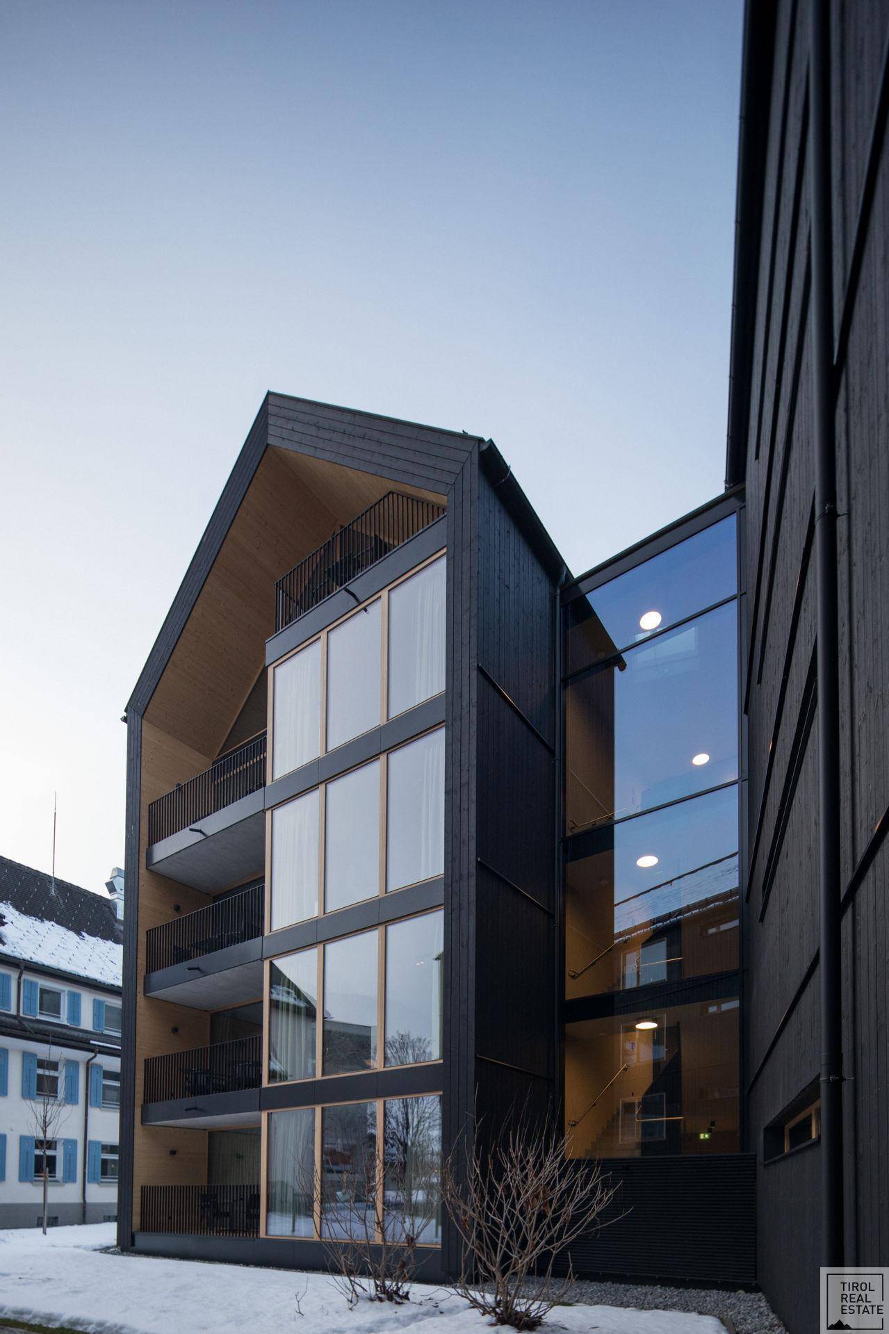 Detailansicht der modernen Fassade mit großen Fenstern und Holzelementen im alpinen Stil.