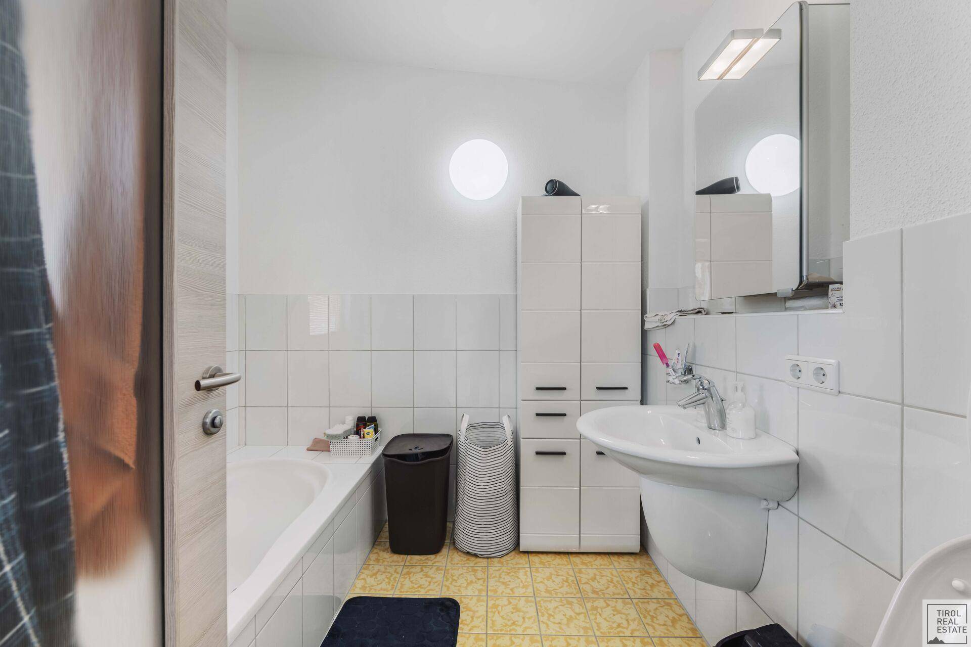 Klassisches Badezimmer mit Badewanne, Waschbecken und weißen Fliesen.