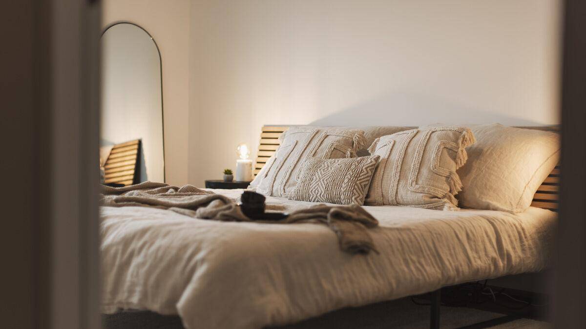 Nahaufnahme eines gemütlichen Bettes mit Kissen und Decke in einem hellen Schlafzimmer.
