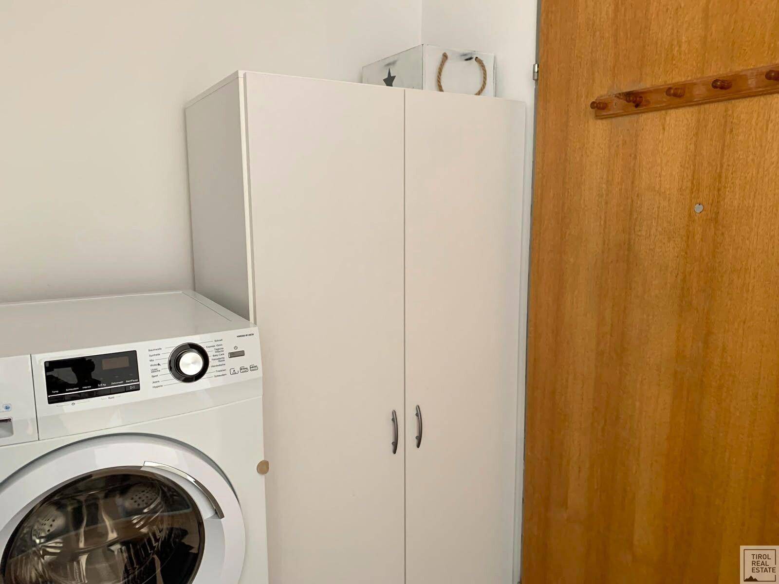 Praktischer Hauswirtschaftsbereich mit Waschmaschine und weißem Schrank, ideal für Wäschepflege.