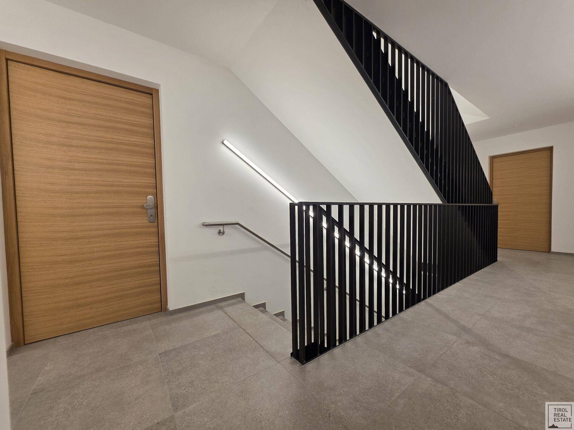 Moderner Treppenabsatz mit Holz-Wohnungstüren und minimalistischem Design.
