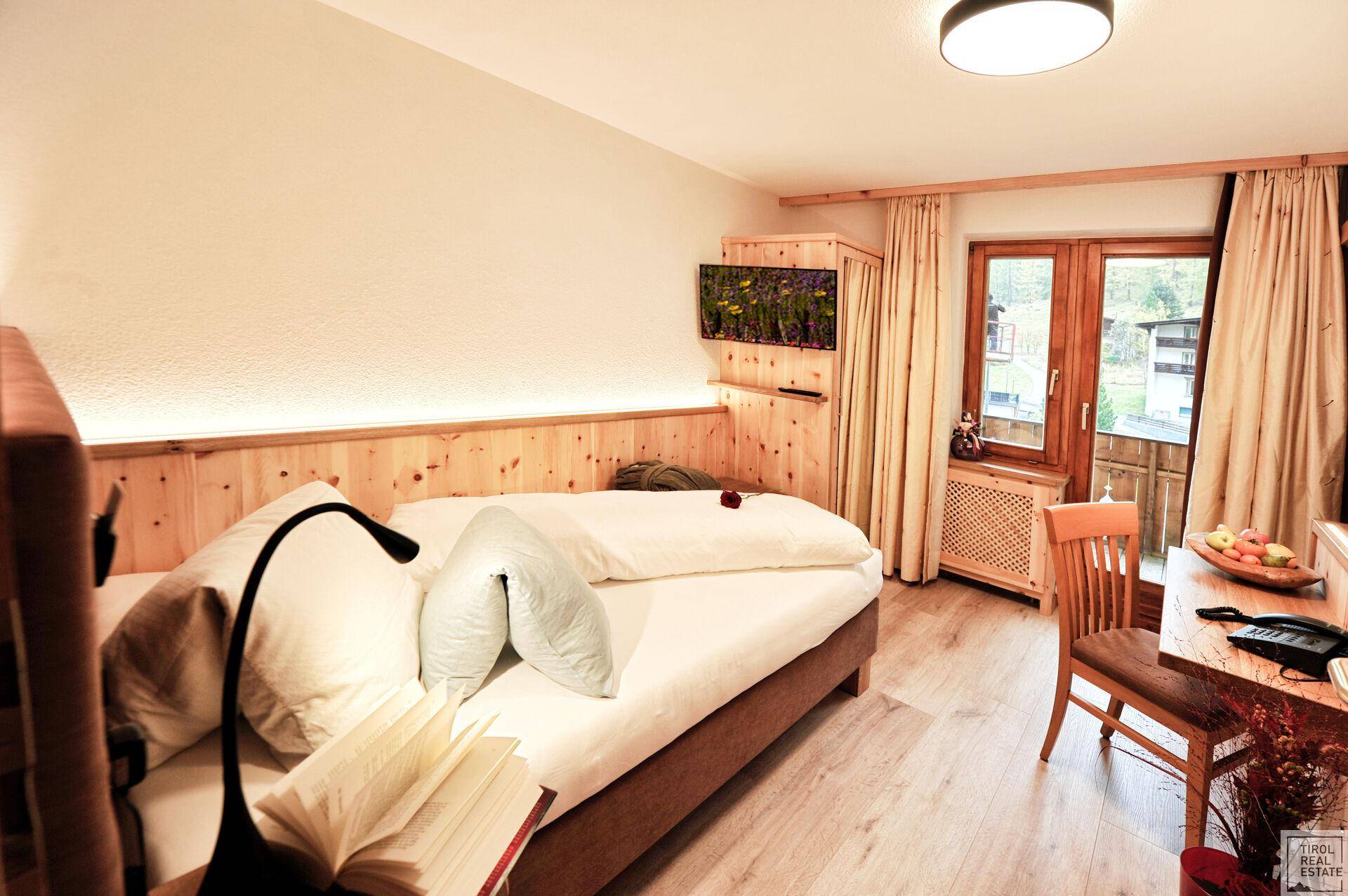 Einzelzimmer mit Holzwandverkleidung, Schreibtisch und Fenster mit Blick auf die Umgebung.