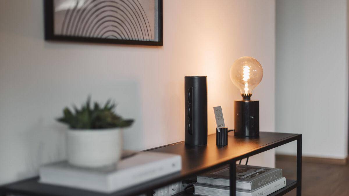 Detailansicht einer Konsole mit Lampe und Dekoration an einer weißen Wand.