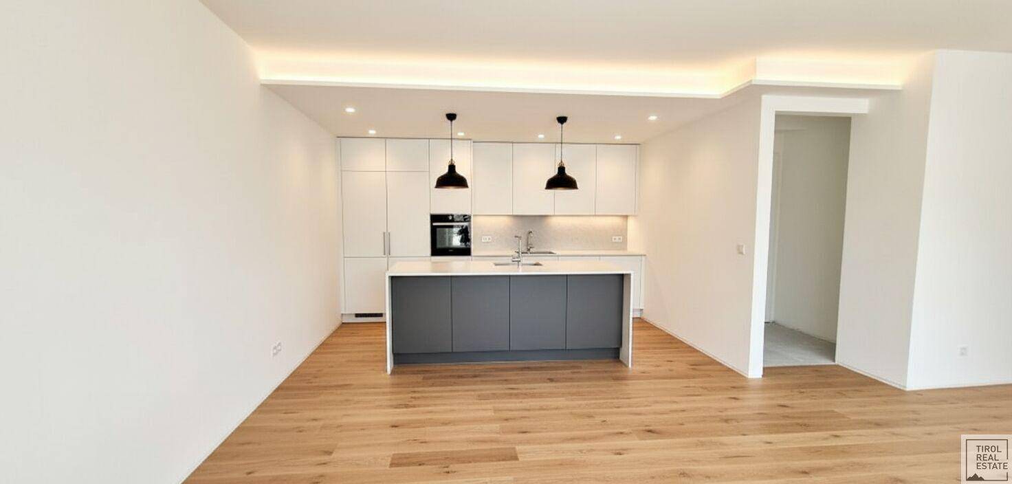 Offene, moderne Küche mit weißer Einbauküche, Kücheninsel und Holzboden.
