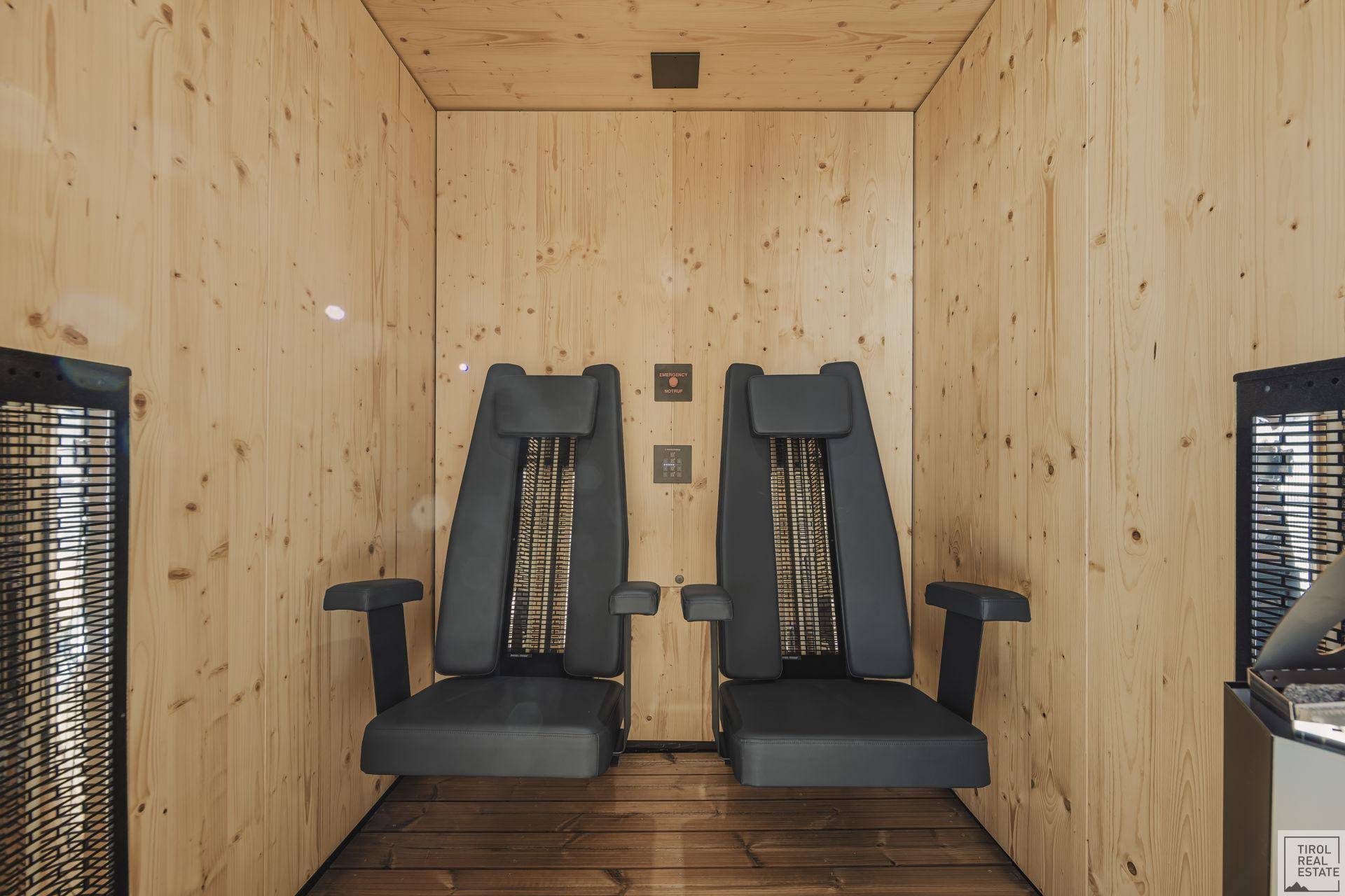 Gemütlicher Wellnessbereich mit Holzwänden und zwei bequemen Infrarot-Sitzen zur Entspannung.