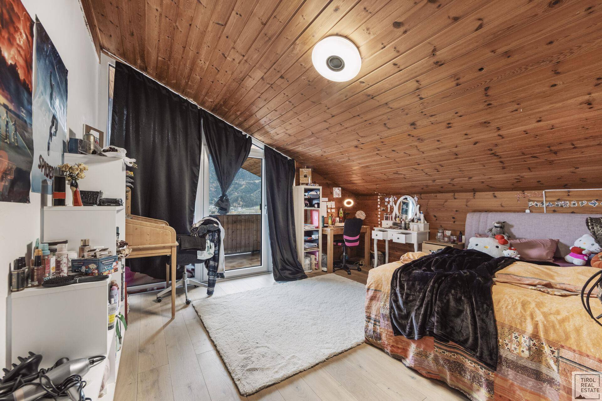 Geräumiges Schlafzimmer im Dachgeschoss mit Holzboden und Balkonzugang.
