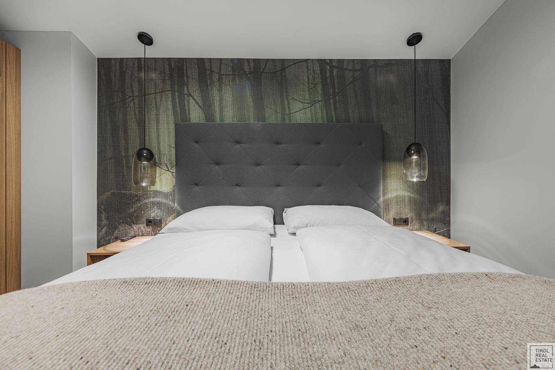 Schlafzimmer mit großem, bequemem Doppelbett und einer auffälligen Waldtapete als Akzentwand.