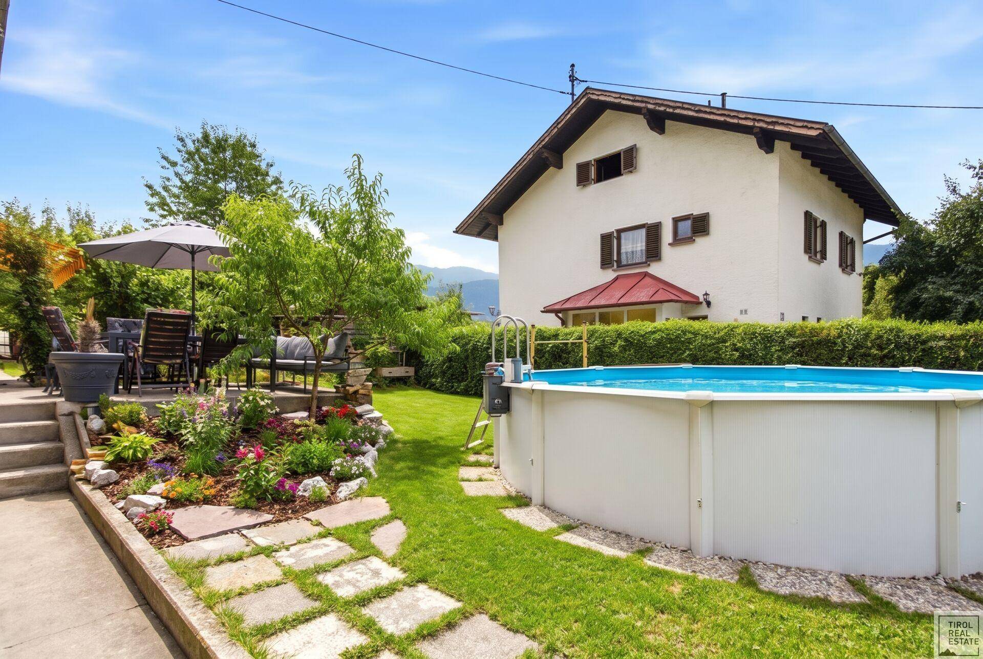 Sonniger Garten mit Aufstellpool, Rasen und möblierter Terrasse für entspannte Stunden.