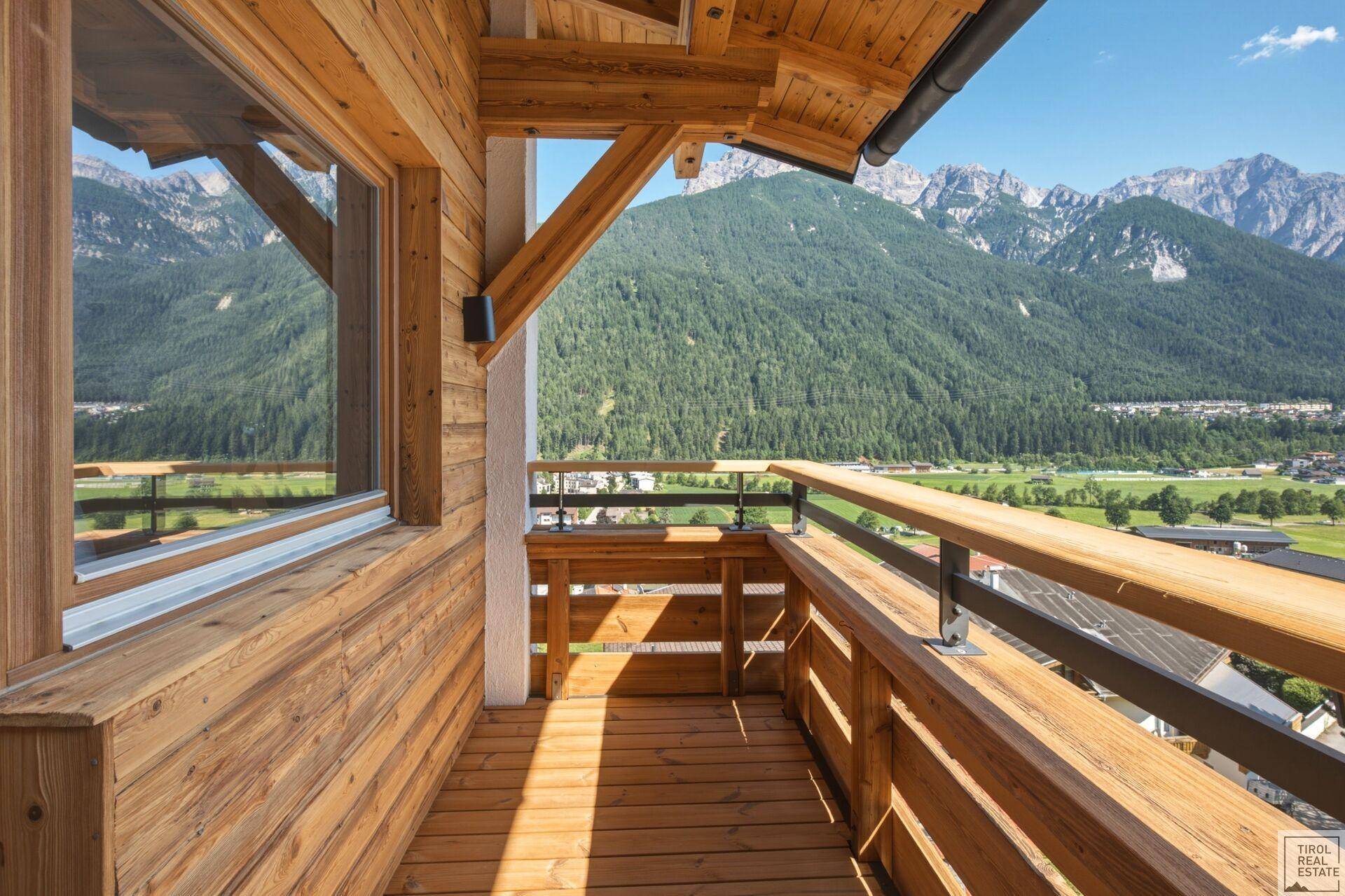 Sonniger Holzbalkon mit atemberaubendem Panoramablick auf die umliegende Bergwelt.