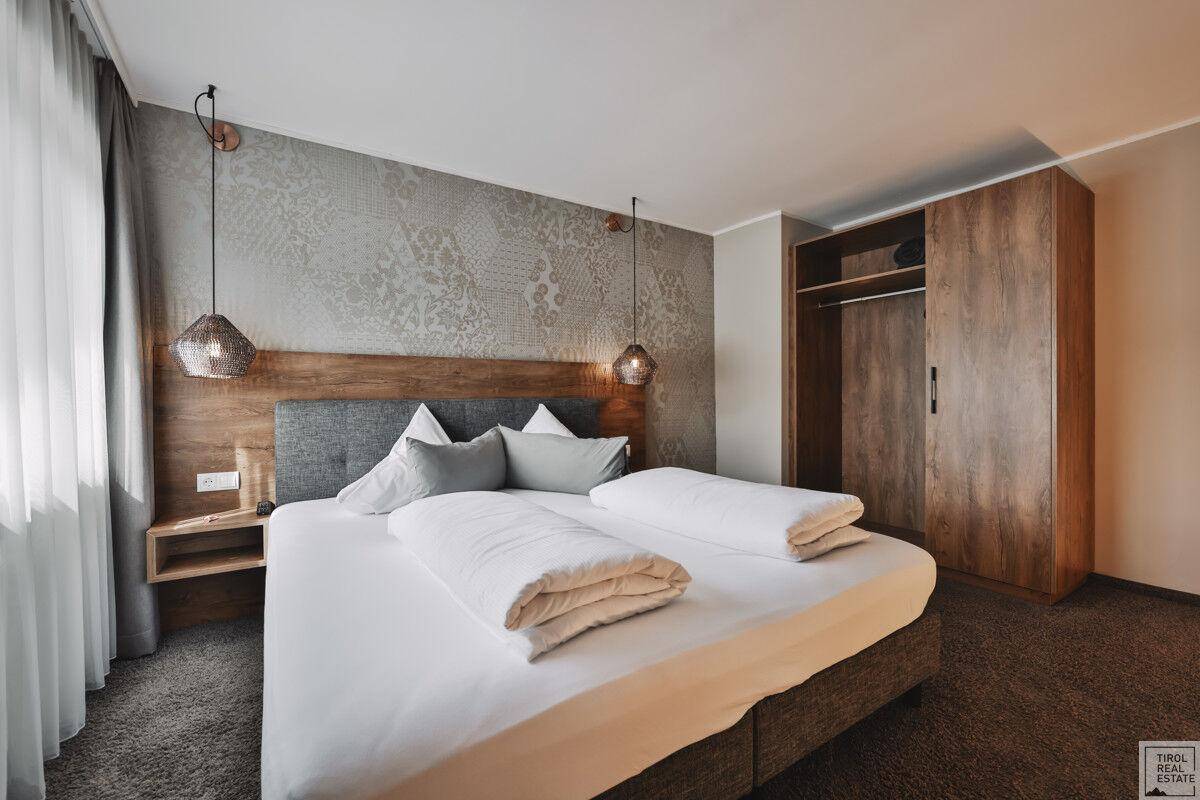 Gemütliches Schlafzimmer mit Doppelbett, Holzelementen und integriertem Kleiderschrank für Stauraum.