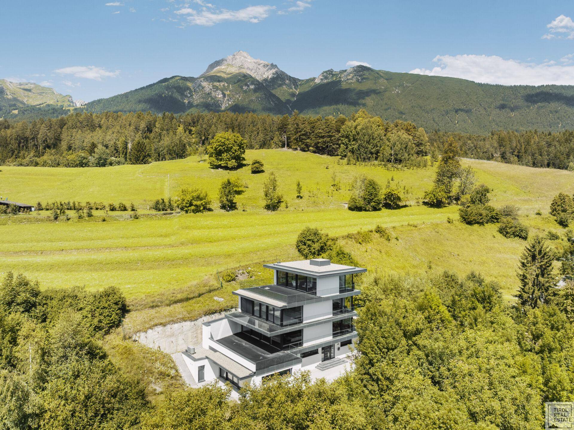 Zeitgenössische Architektur der Villa eingebettet in die alpine Landschaft mit weitem Bergblick.