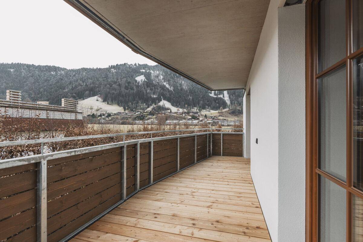 Großer Balkon mit Holzbelag und Bergblick, ideal für entspannte Stunden im Freien.
