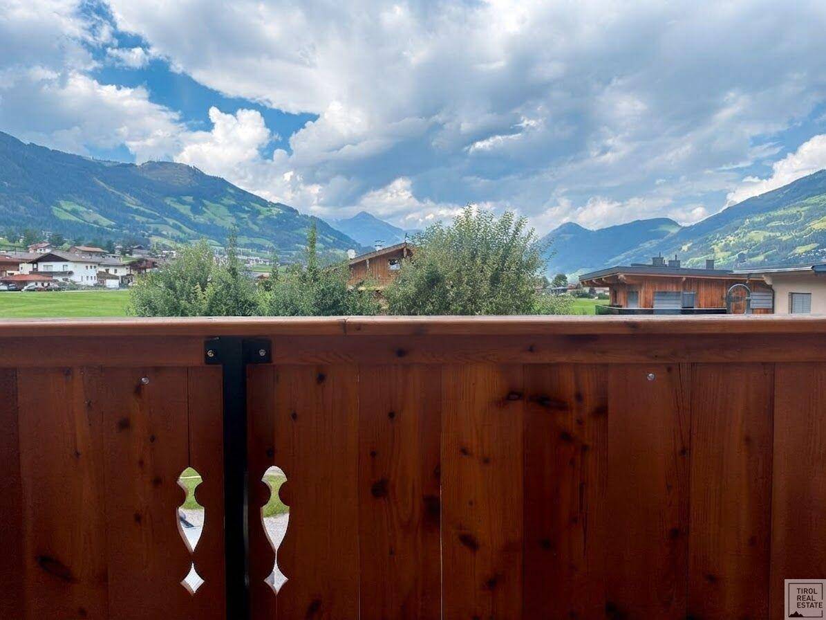 Panoramablick vom Balkon auf die majestätische Bergwelt und grüne Wiesen.