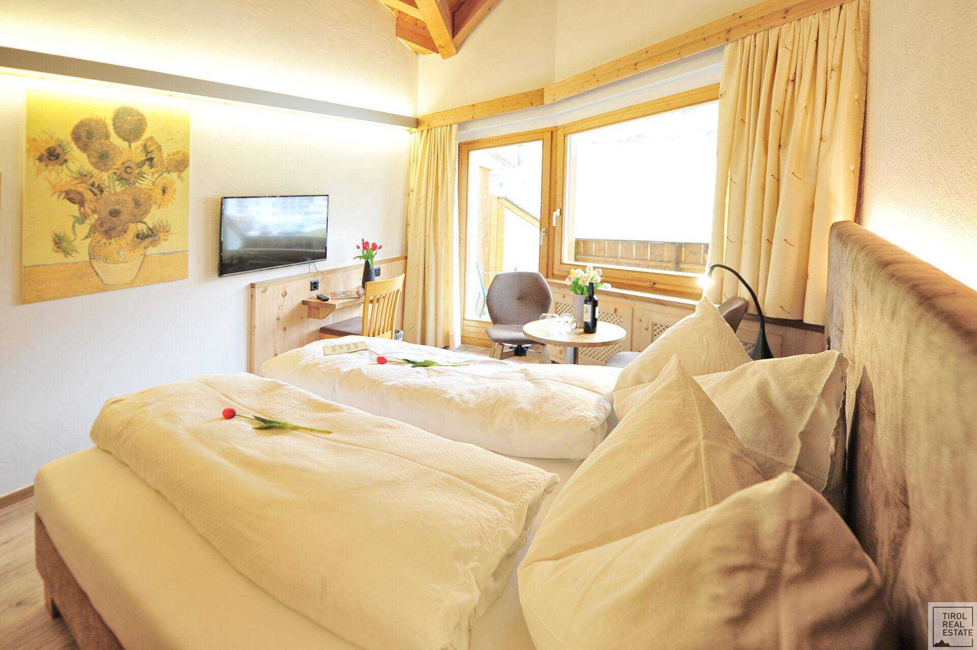 Schlafzimmer mit zwei Einzelbetten, Holzelementen und einem Fenster mit Blick auf die Natur.