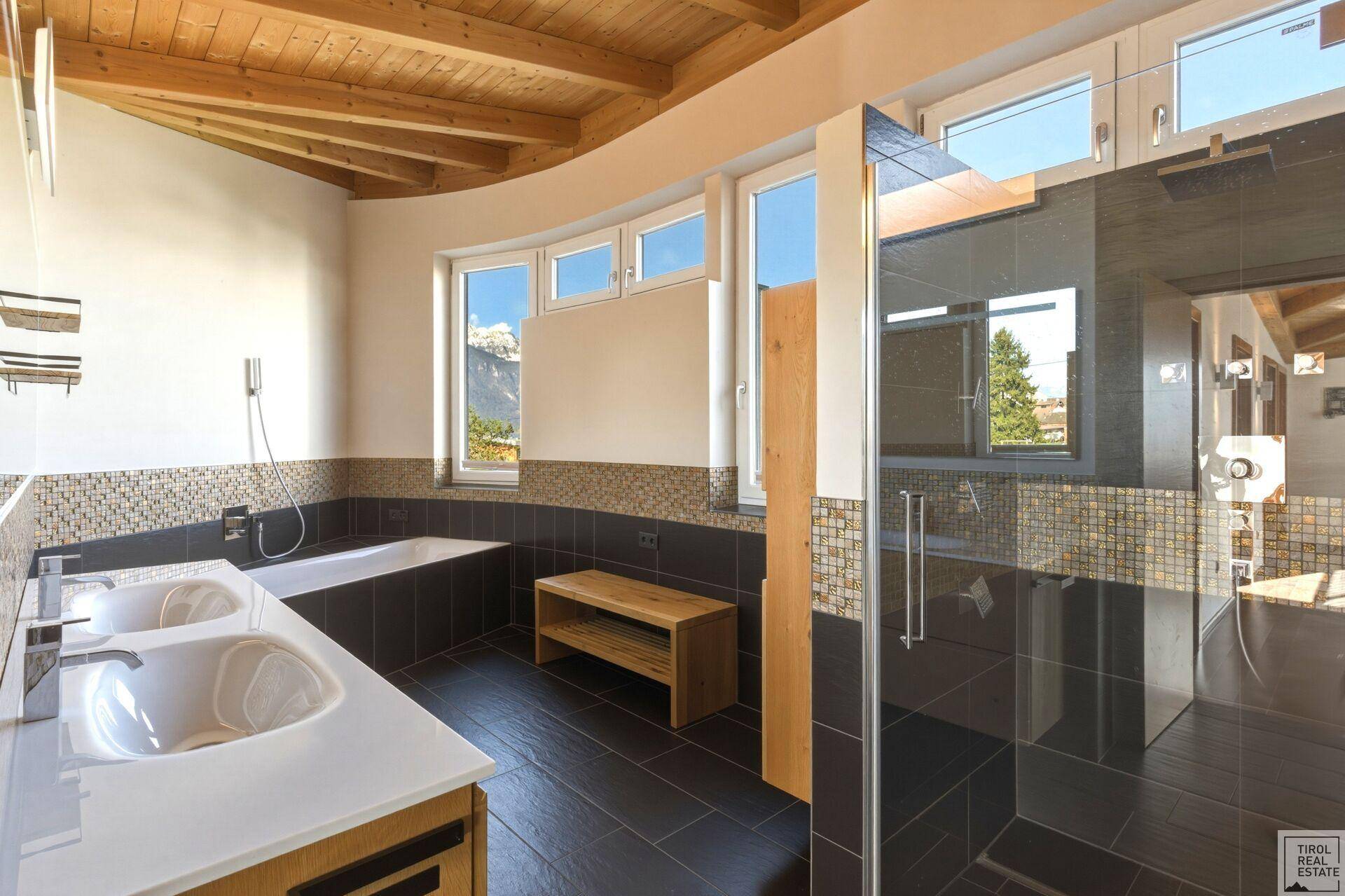 Elegantes Badezimmer mit Doppelwaschbecken, Badewanne und großer Dusche, mit Bergblick.