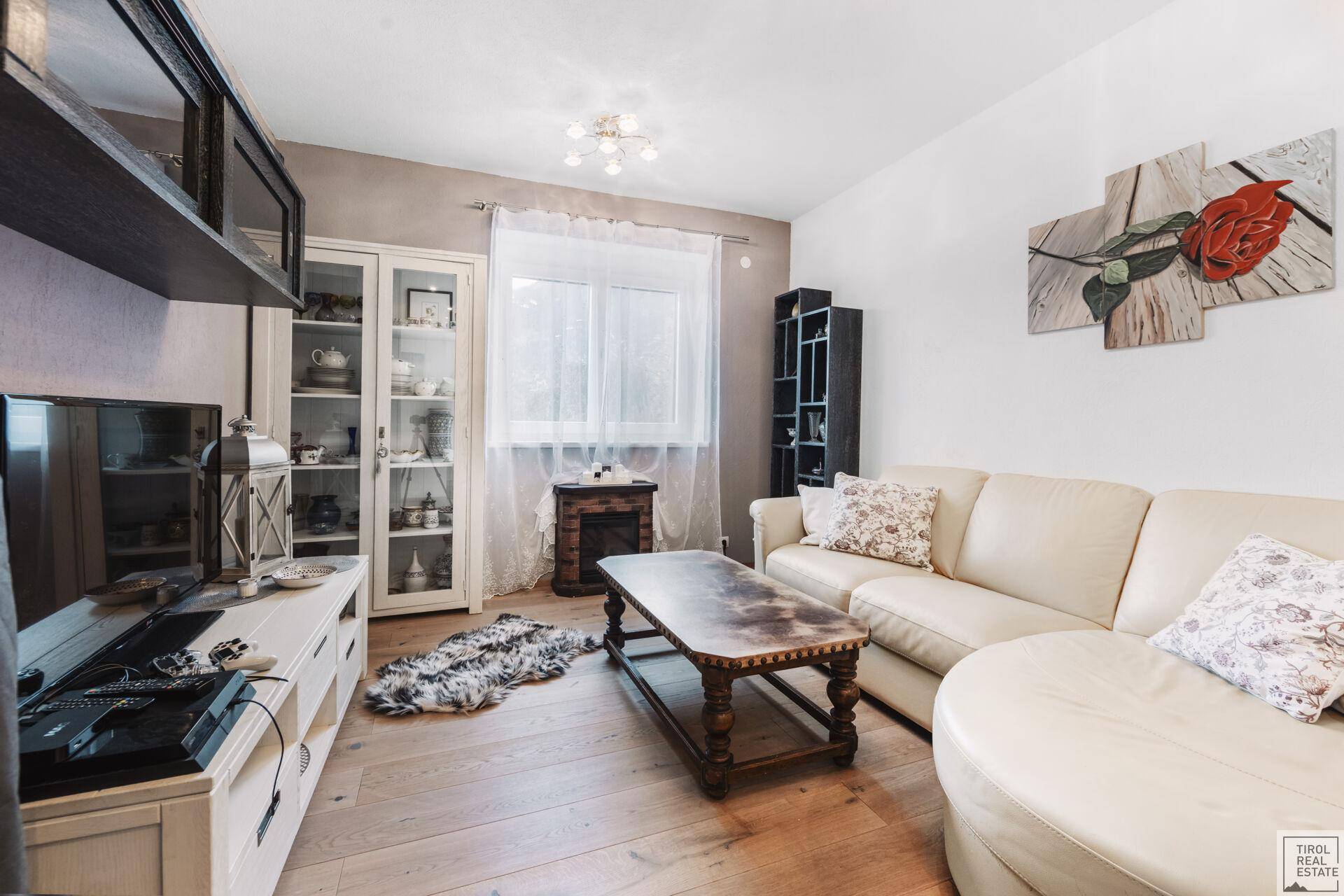 Gemütliches Wohnzimmer mit hellem Sofa, Holzboden und dekorativem Kamin.