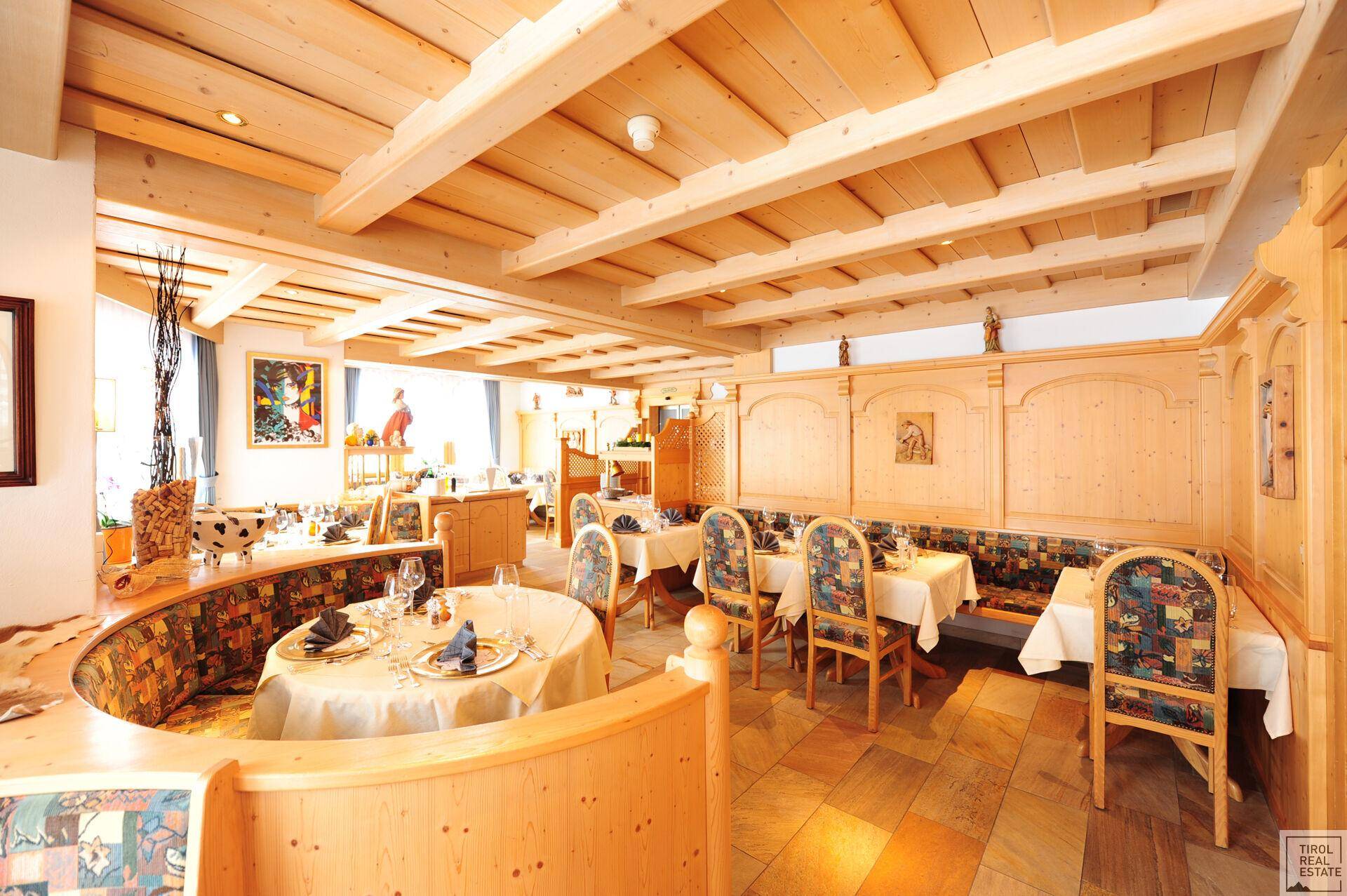 Traditioneller Speisesaal mit Holzbalkendecke, Holzvertäfelung und elegant gedeckten Tischen für Gäste.
