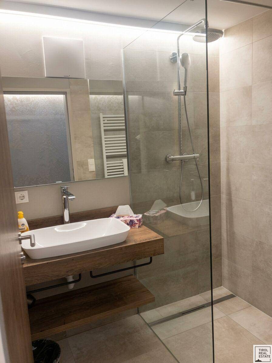 Modernes Badezimmer mit ebenerdiger Dusche, stilvollem Waschbecken und hellen Fliesen.