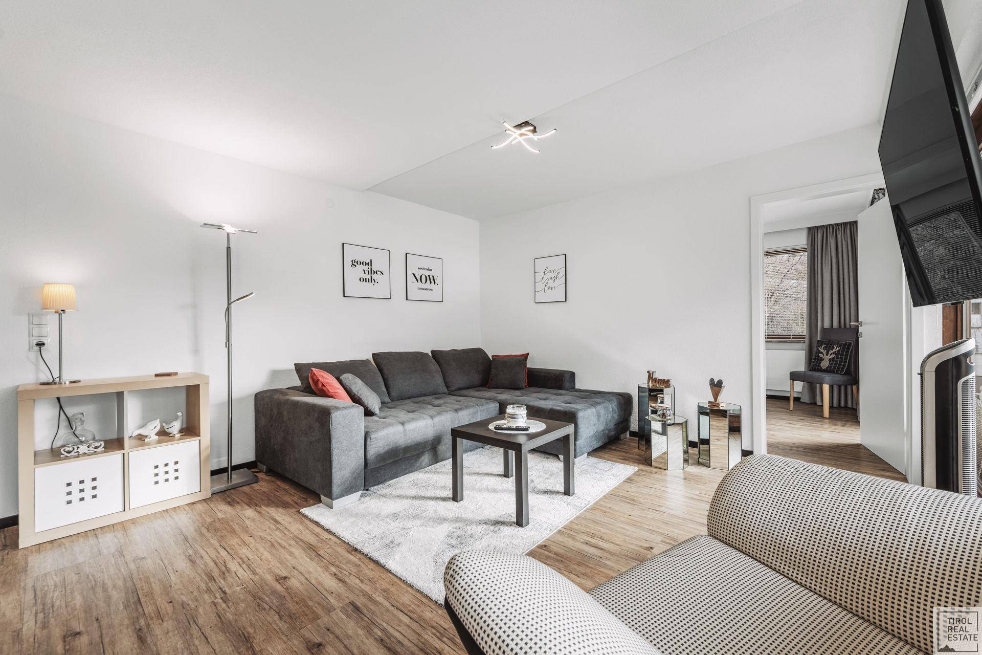 Gemütliches Wohnzimmer mit großem Ecksofa, Holzboden und moderner Dekoration.
