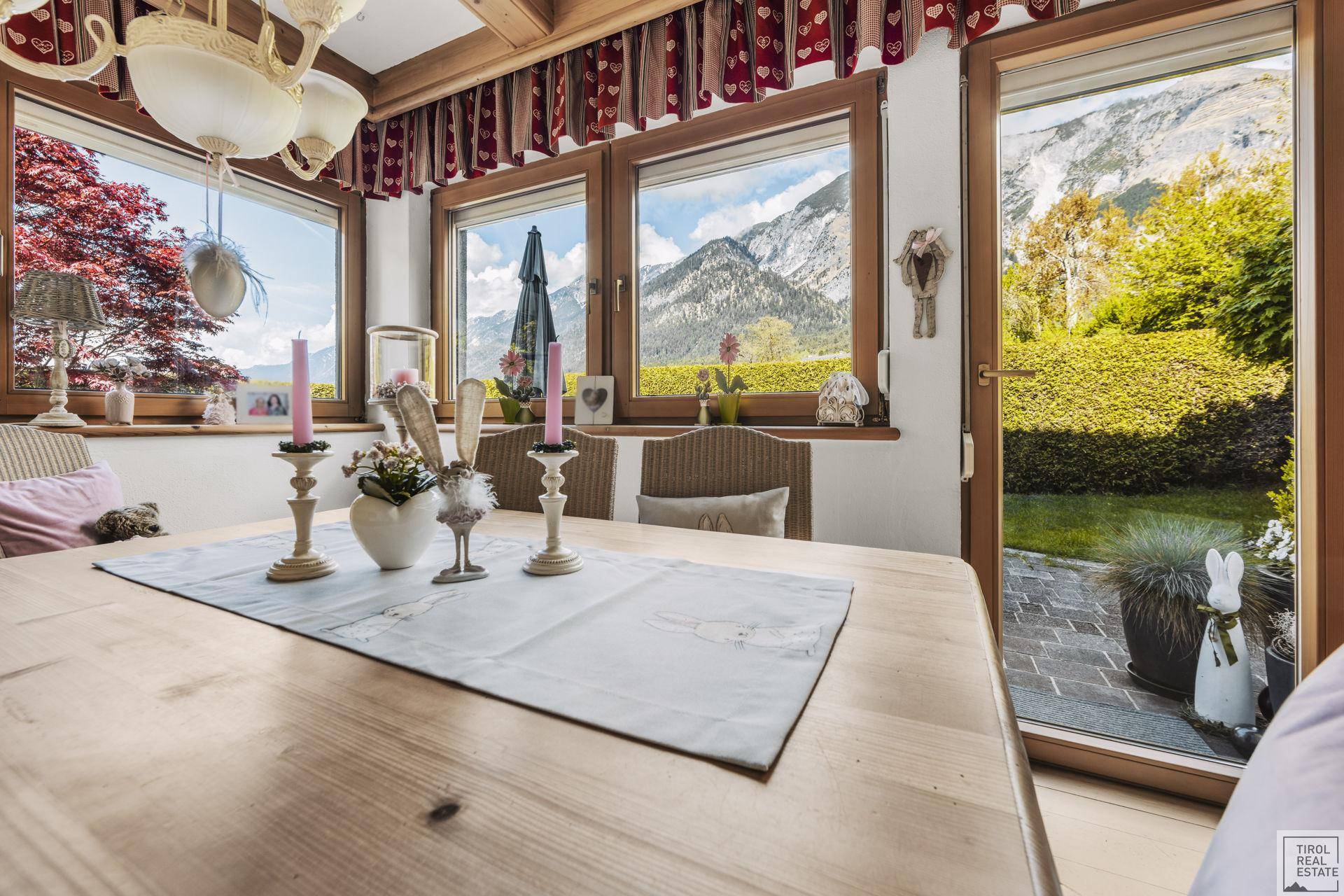 Detailansicht des Esstisches mit Dekoration und weitem Blick auf die Berge und den Garten.
