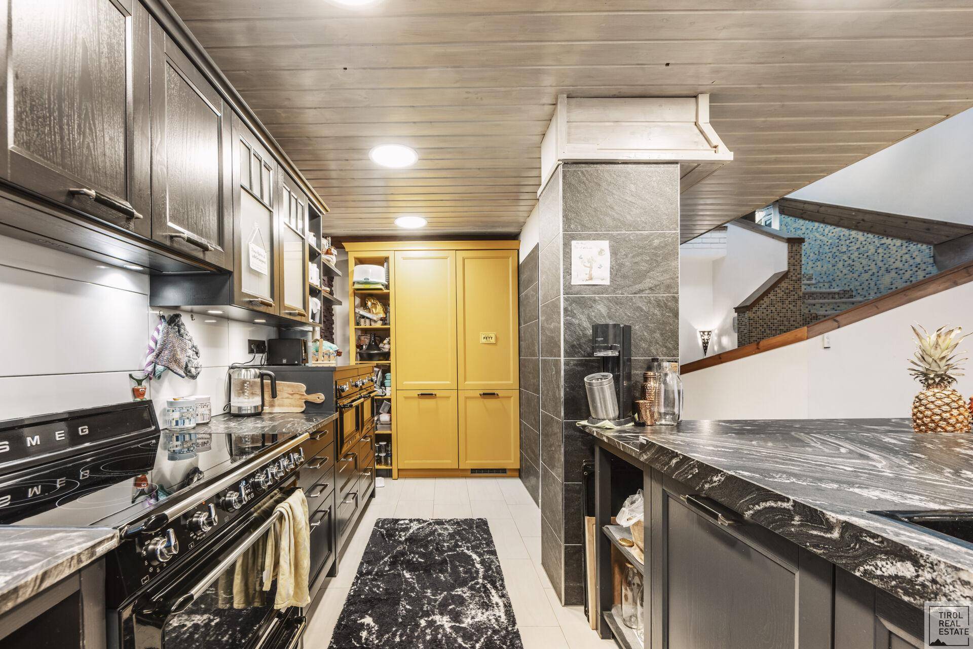 Gut ausgestattete Küche mit dunklen Schränken, Granitarbeitsplatten und viel Stauraum.