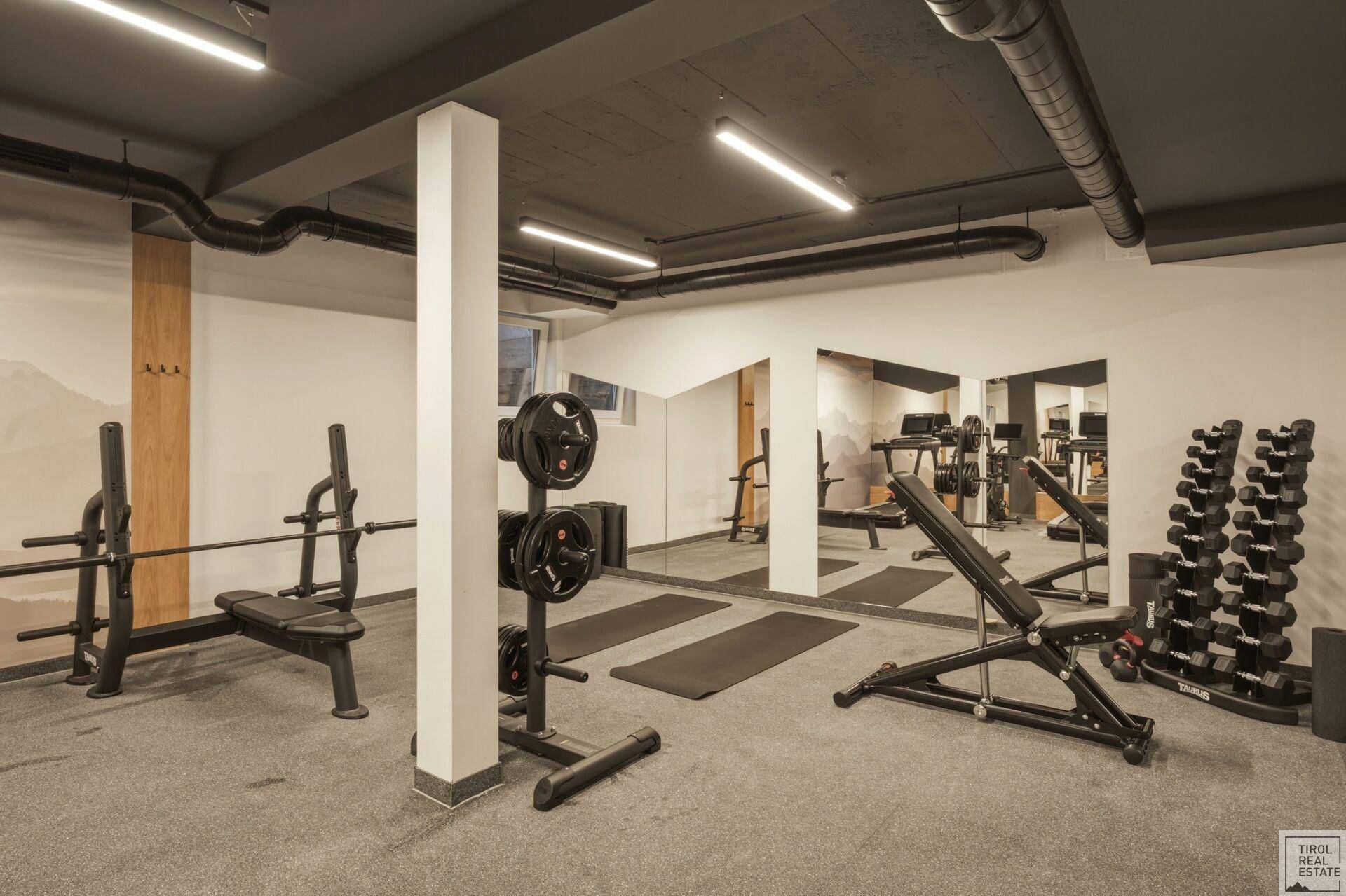 Geräumiger Fitnessraum mit Hantelstangen, Gewichten und Matten für vielseitiges Training.