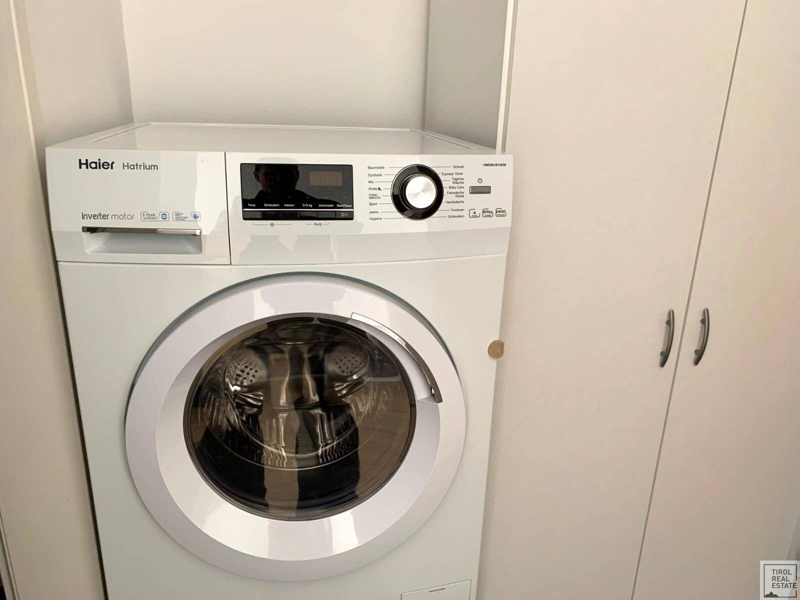 Nahaufnahme einer modernen Waschmaschine der Marke Haier, integriert in einen Hauswirtschaftsbereich.