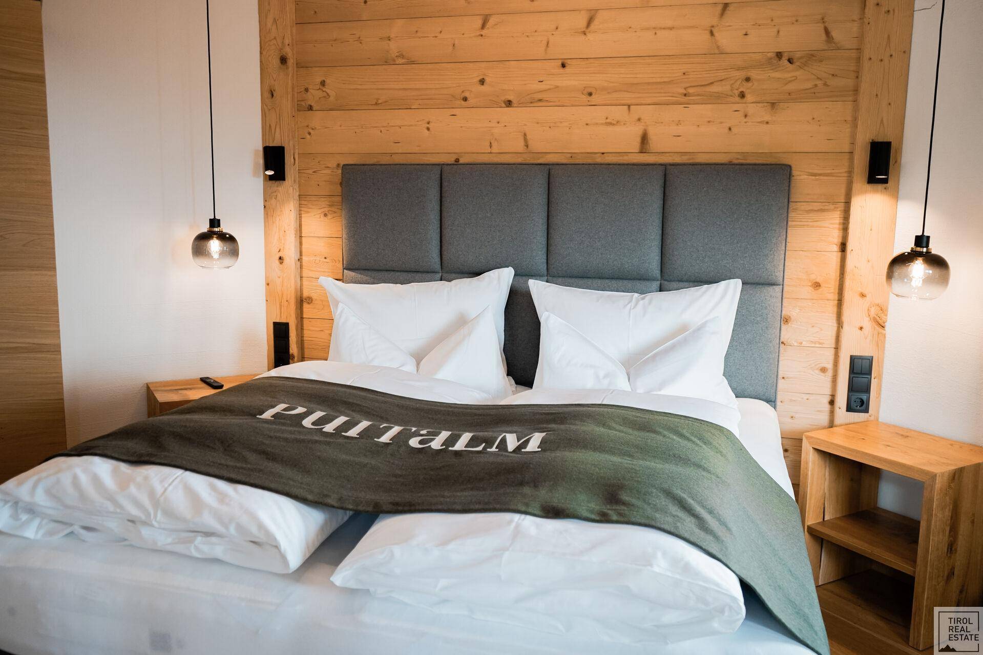 Komfortables Schlafzimmer mit Holzwänden, großem Doppelbett und stilvollen Hängelampen.