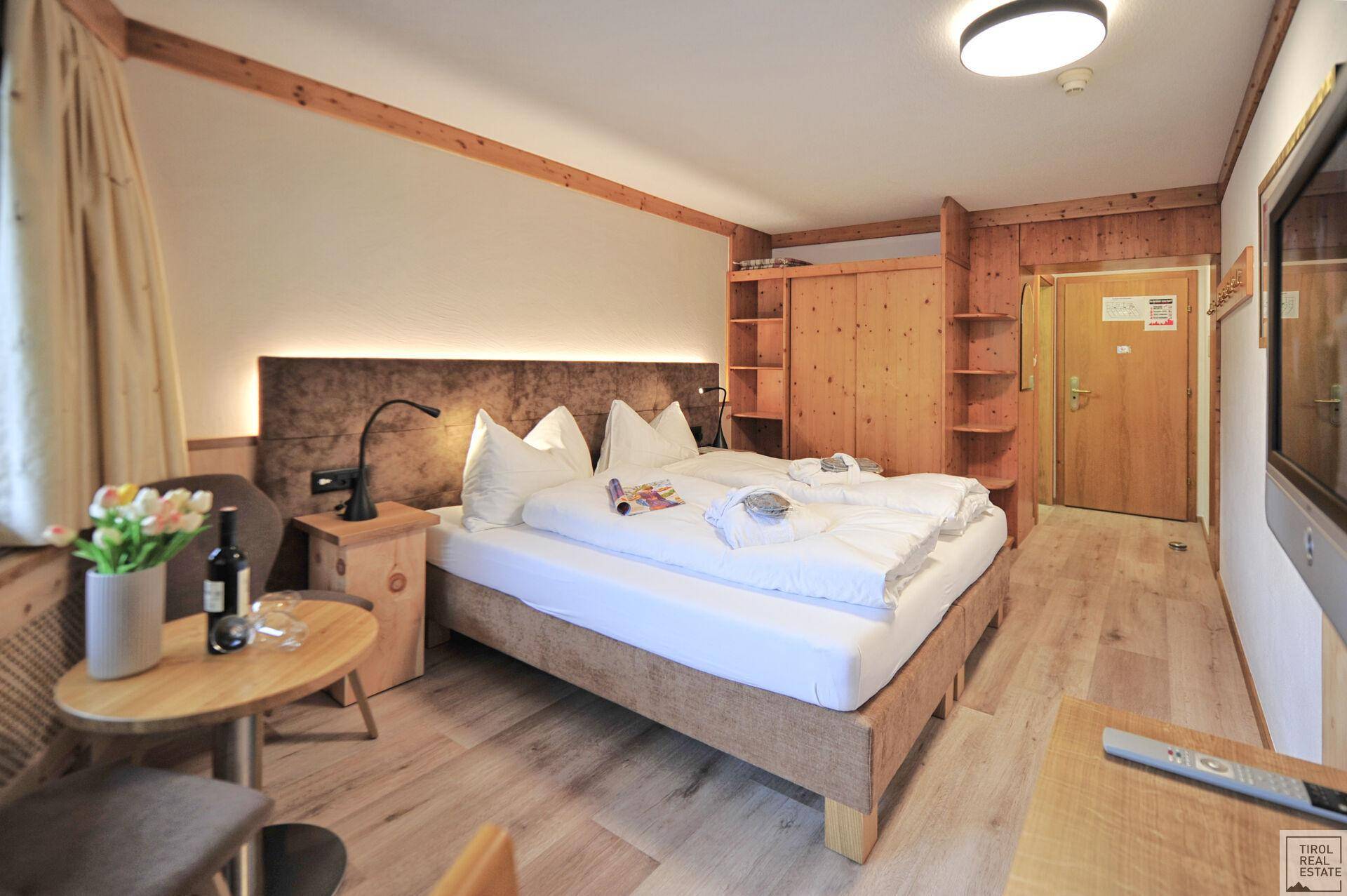 Schlafzimmer mit Doppelbett, integriertem Kleiderschrank und einem kleinen Tisch mit Stühlen.