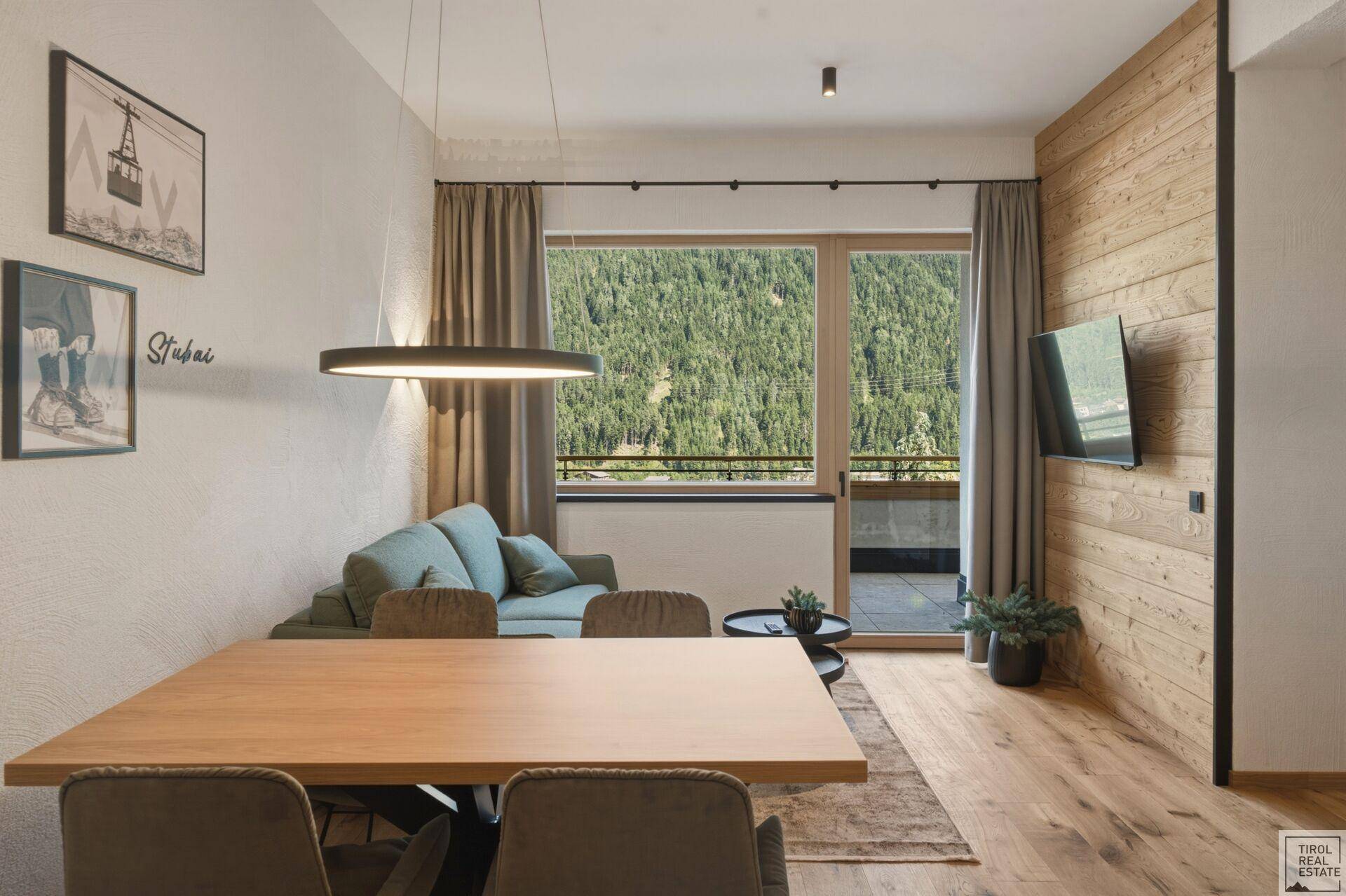 Heller Wohn- und Essbereich mit Holzboden und Zugang zum Balkon mit Bergblick.