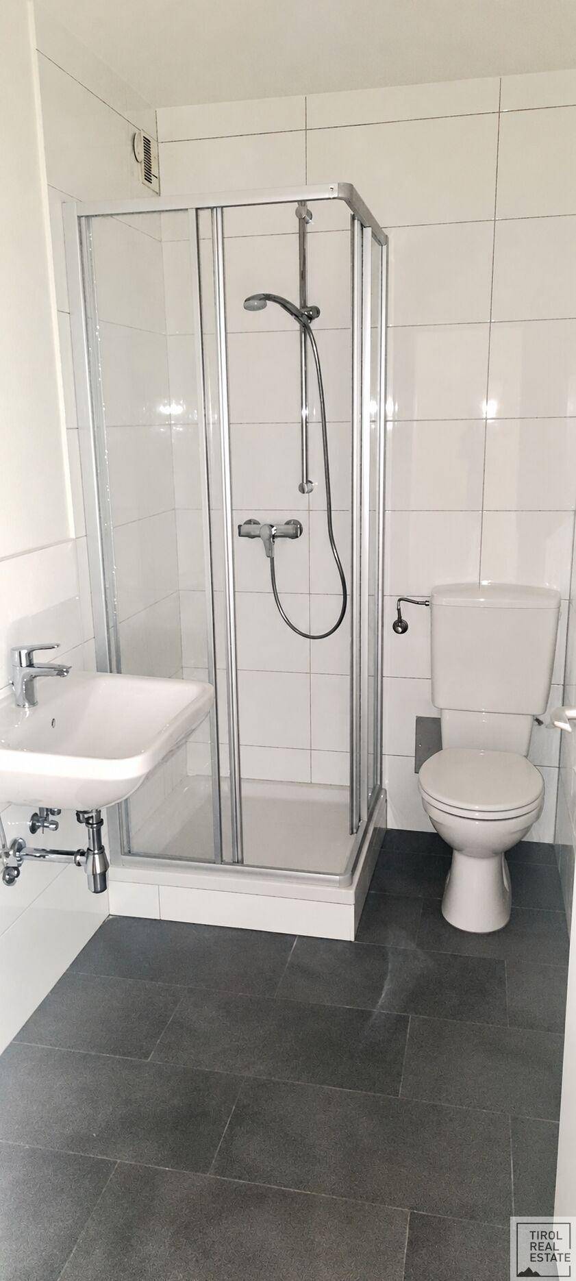 Modernes Badezimmer mit Duschkabine, WC und Waschbecken, hell gefliest.