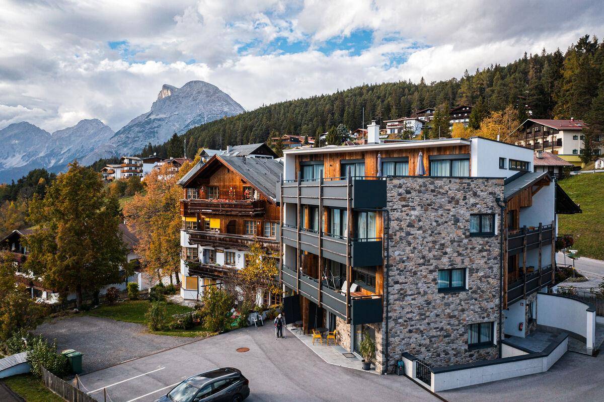 Moderne Architektur mit Steinfassade und Balkonen, eingebettet in eine alpine Landschaft.