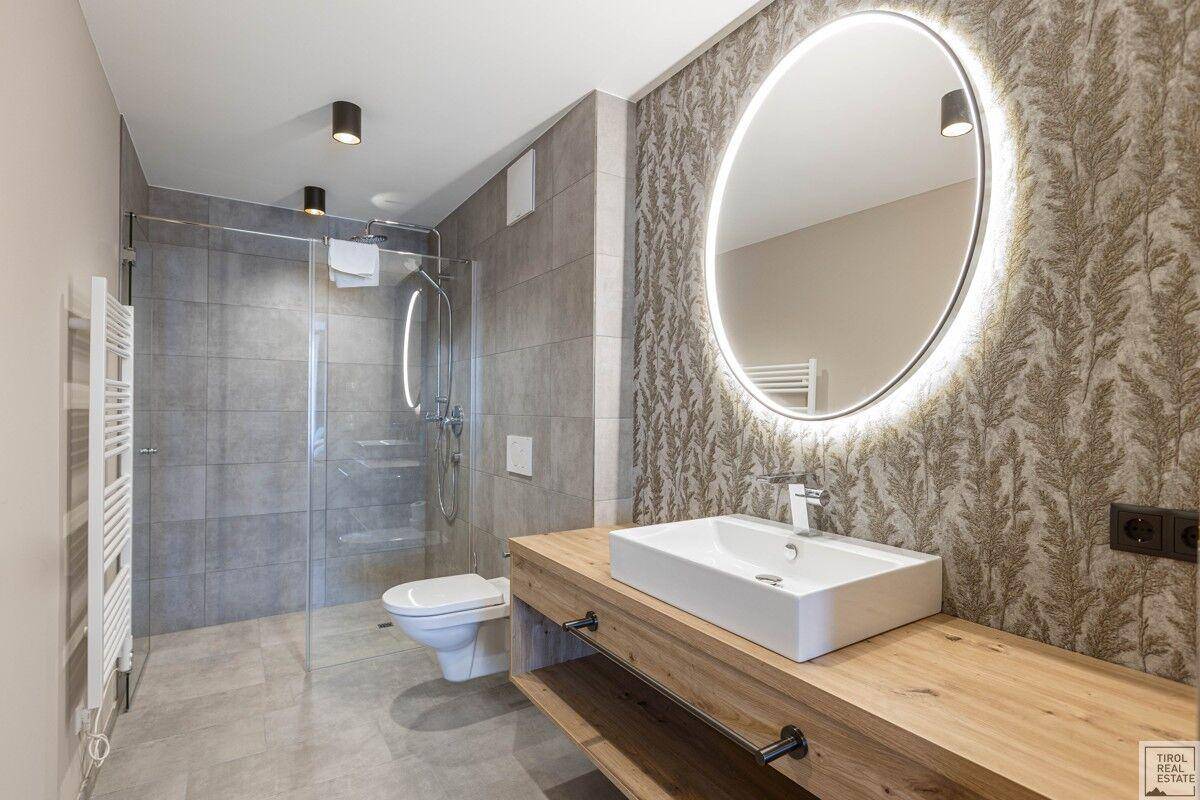 Modernes Badezimmer mit begehbarer Dusche, großem Spiegel und Holzwaschtisch.