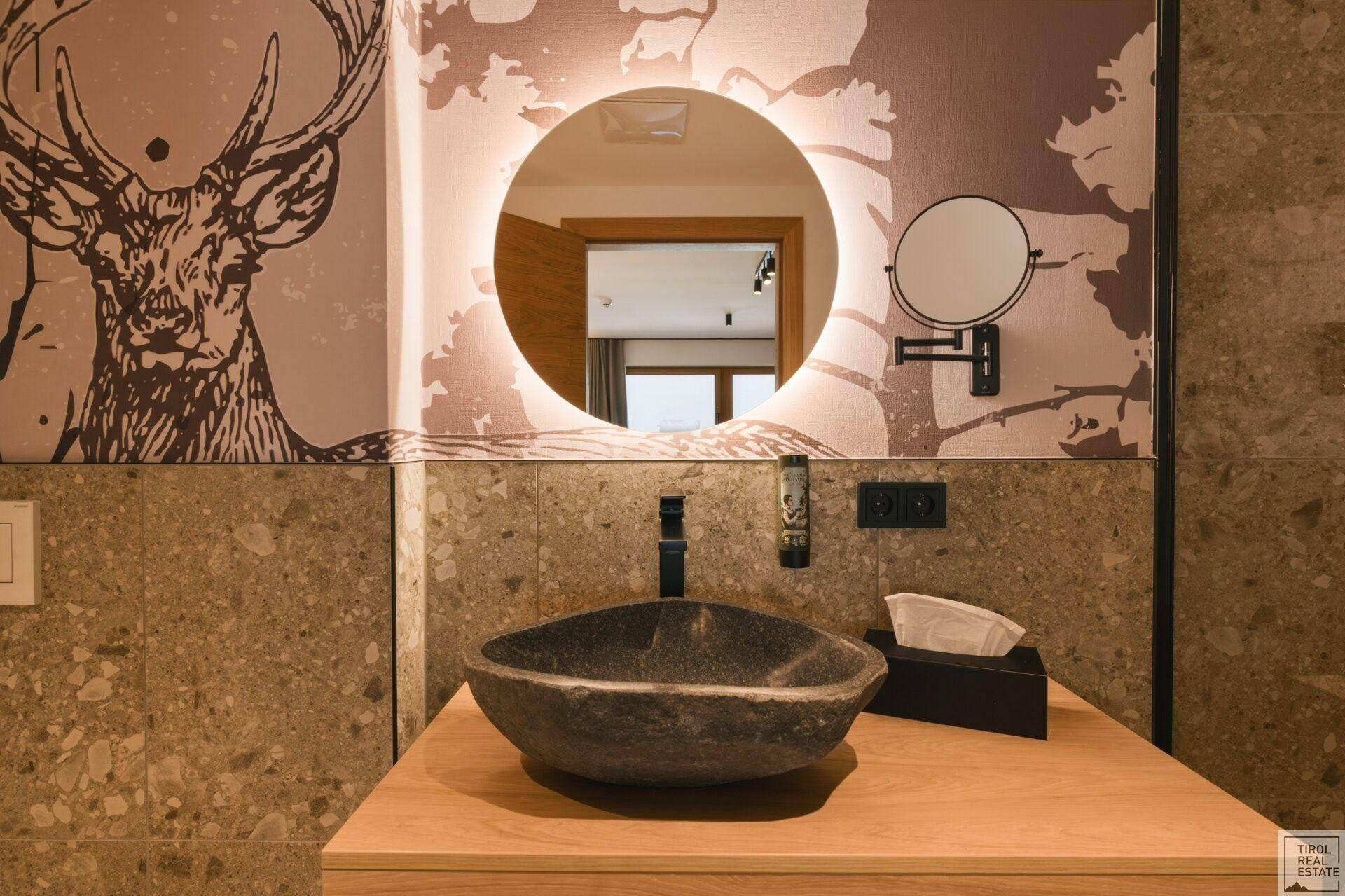 Nahaufnahme des Badezimmerwaschtisches mit einzigartigem Steinwaschbecken und modernem Spiegel.