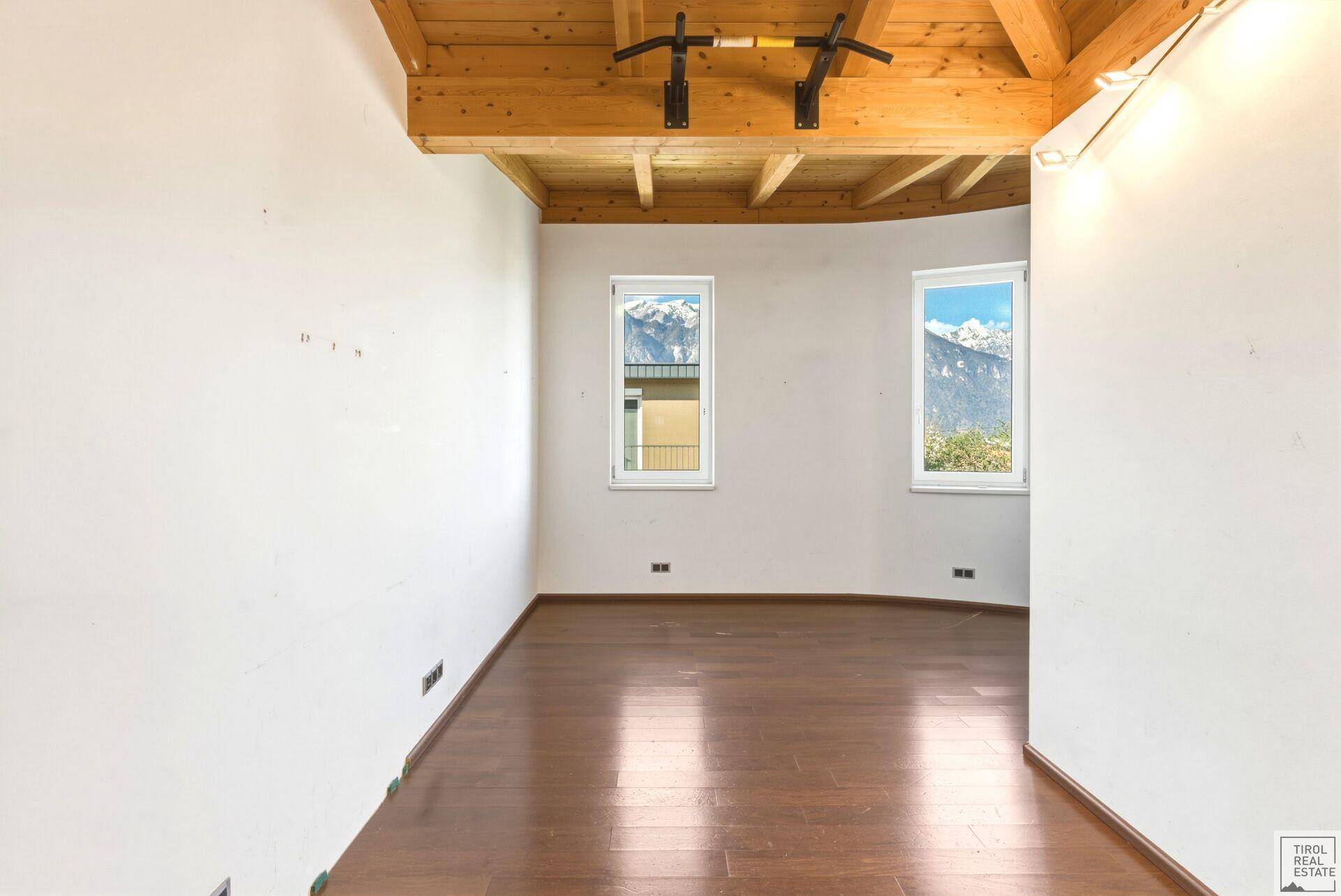 Geräumiges Schlafzimmer mit Holzboden und Holzbalkendecke, ideal für ein Fitnessgerät.